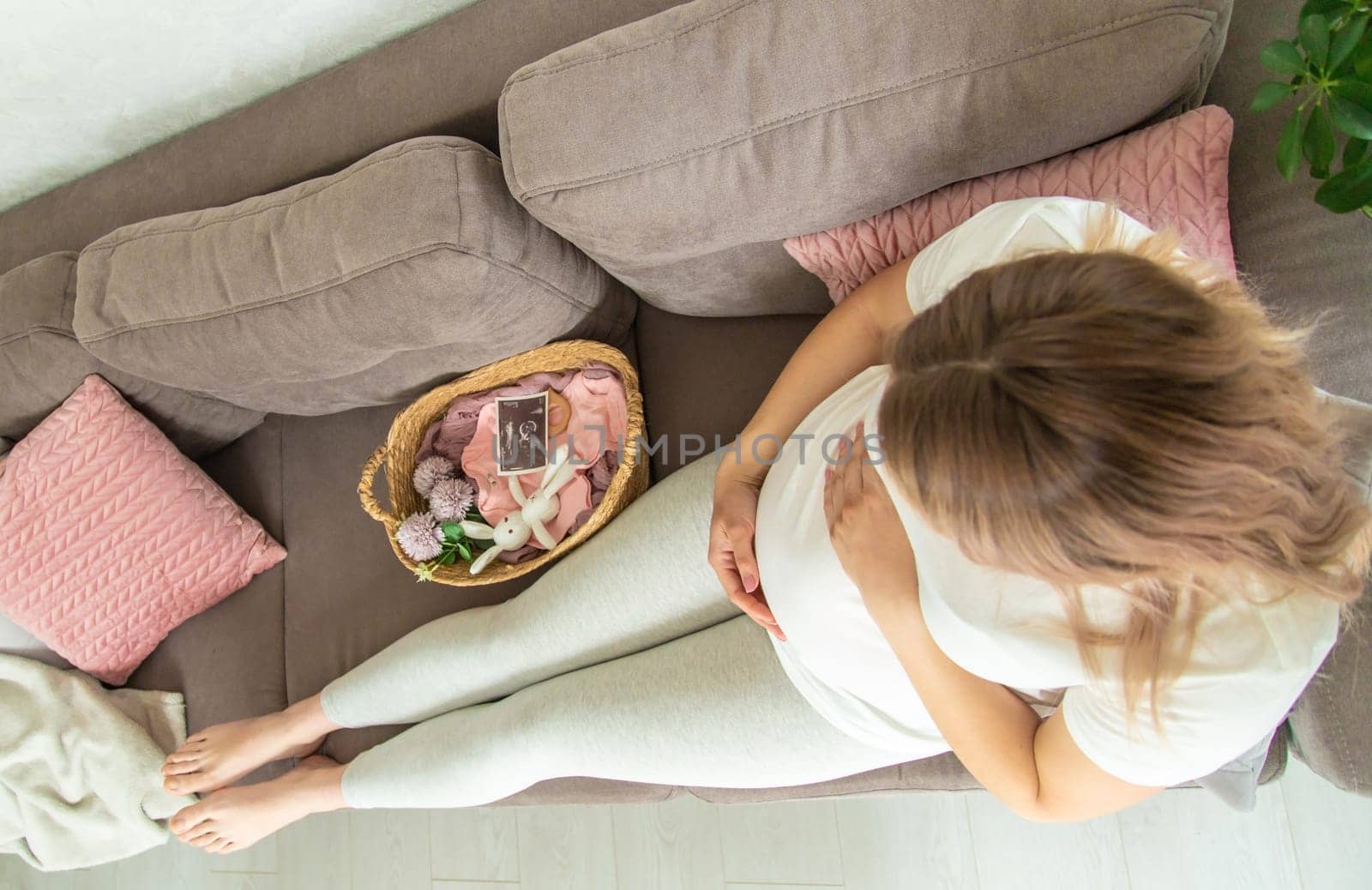 A pregnant woman looks at baby cloth and an ultrasound photo. Selective focus. by Anuta23