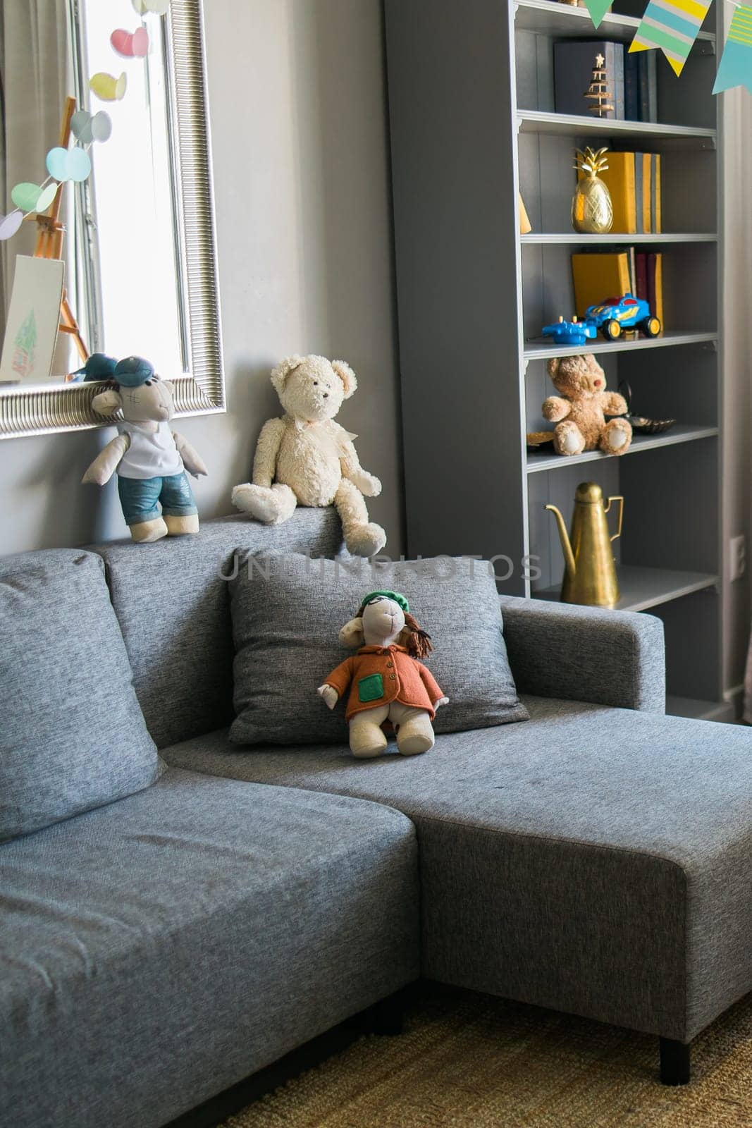 Stylish scandinavian nursery interior with shelves teddy bear and toys. Hanging flags cozy and sunny child room concept