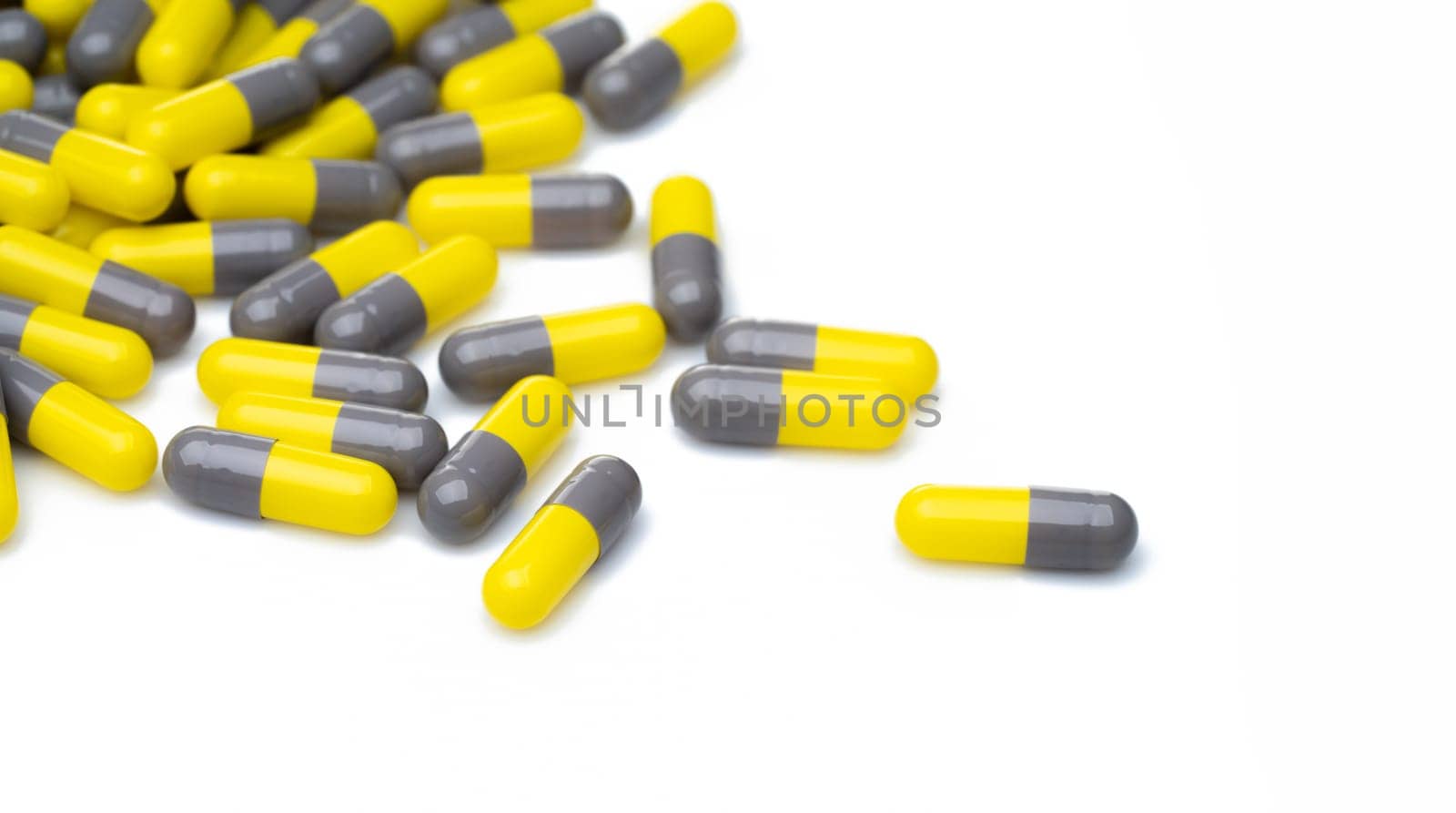 Yellow and gray probiotic capsule pill on white background. Probiotic supplement. Gut health. Dietary supplements. Probiotics for a healthy gut. Lactobacillus acidophilus and Bifidobacterium animalis. by Fahroni