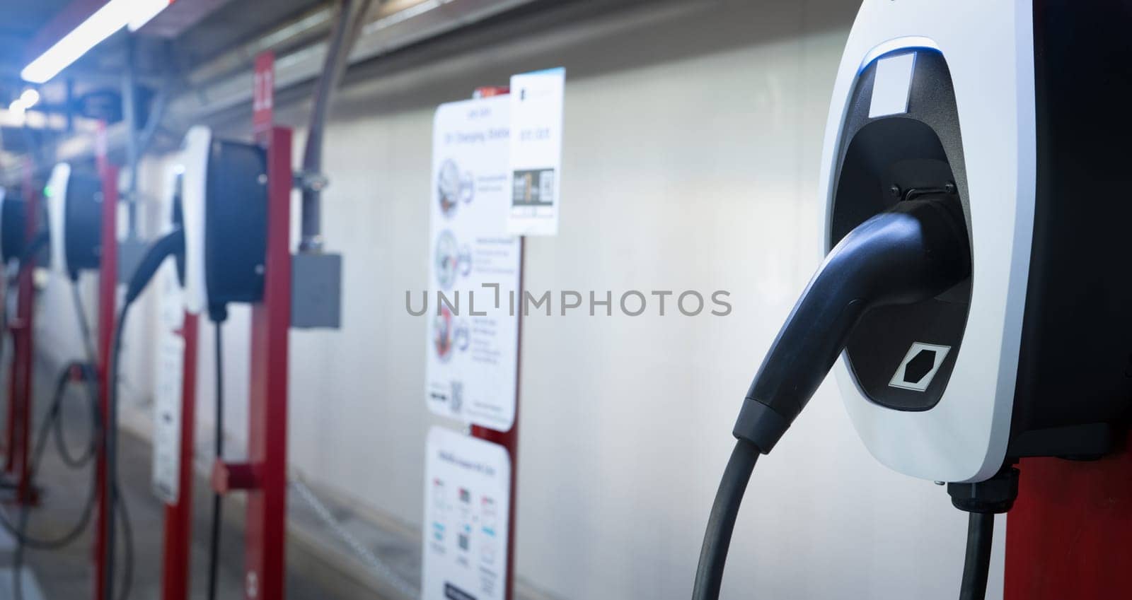 Electric car charging station for charge EV battery. Plug for electric vehicle. EV charger. Charging point at car parking lot of the mall. Clean and sustainable energy. Commercial EV charging point. by Fahroni