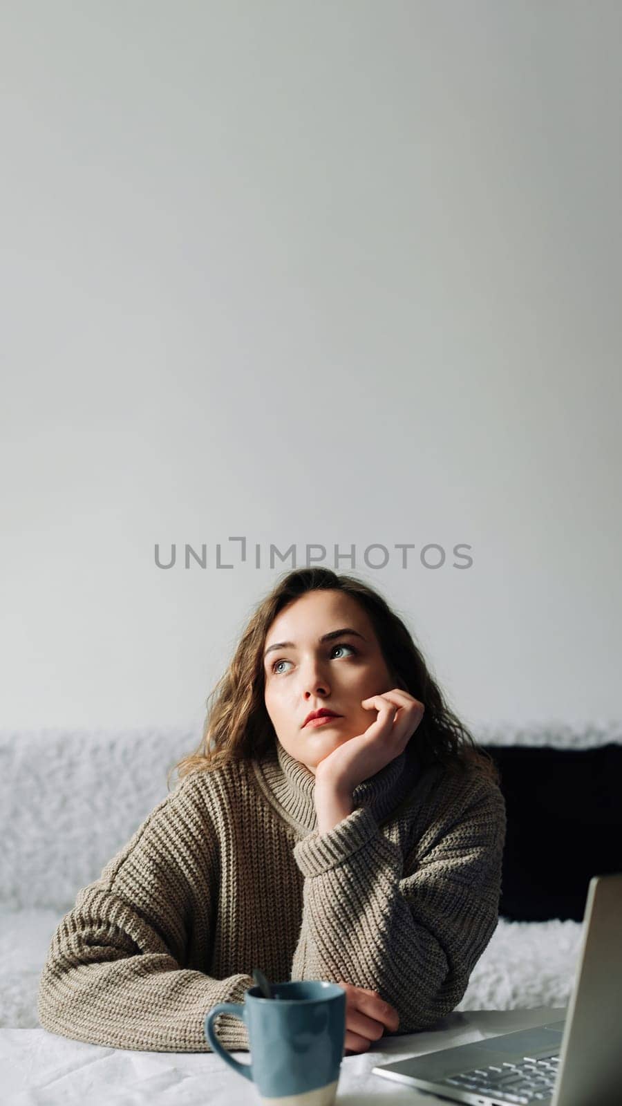 Creative woman working from home writing lesson plan and schedule for students, using laptop and sipping coffee at kitchen table. Productive teacher writes outline and schedule at laptop.