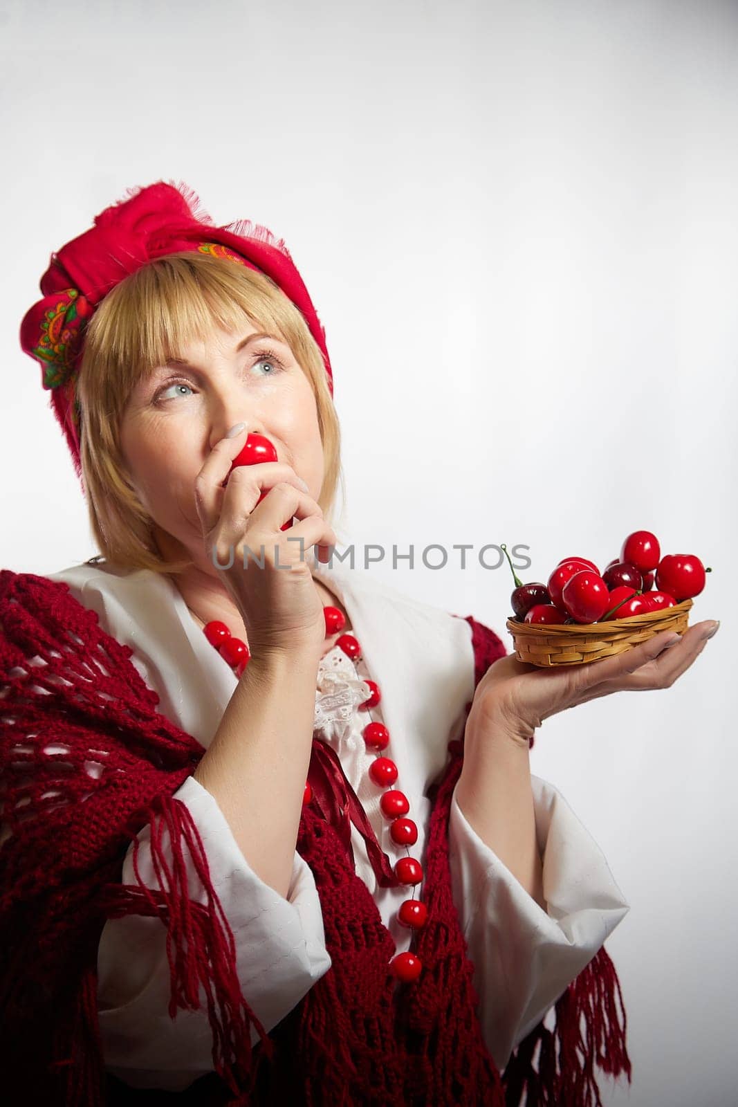 Portrait of heerful funny adult mature woman solokha with red berries. Female model in clothes of national ethnic Slavic style. Stylized Ukrainian, Belarusian or Russian woman in comic photo shoot by keleny