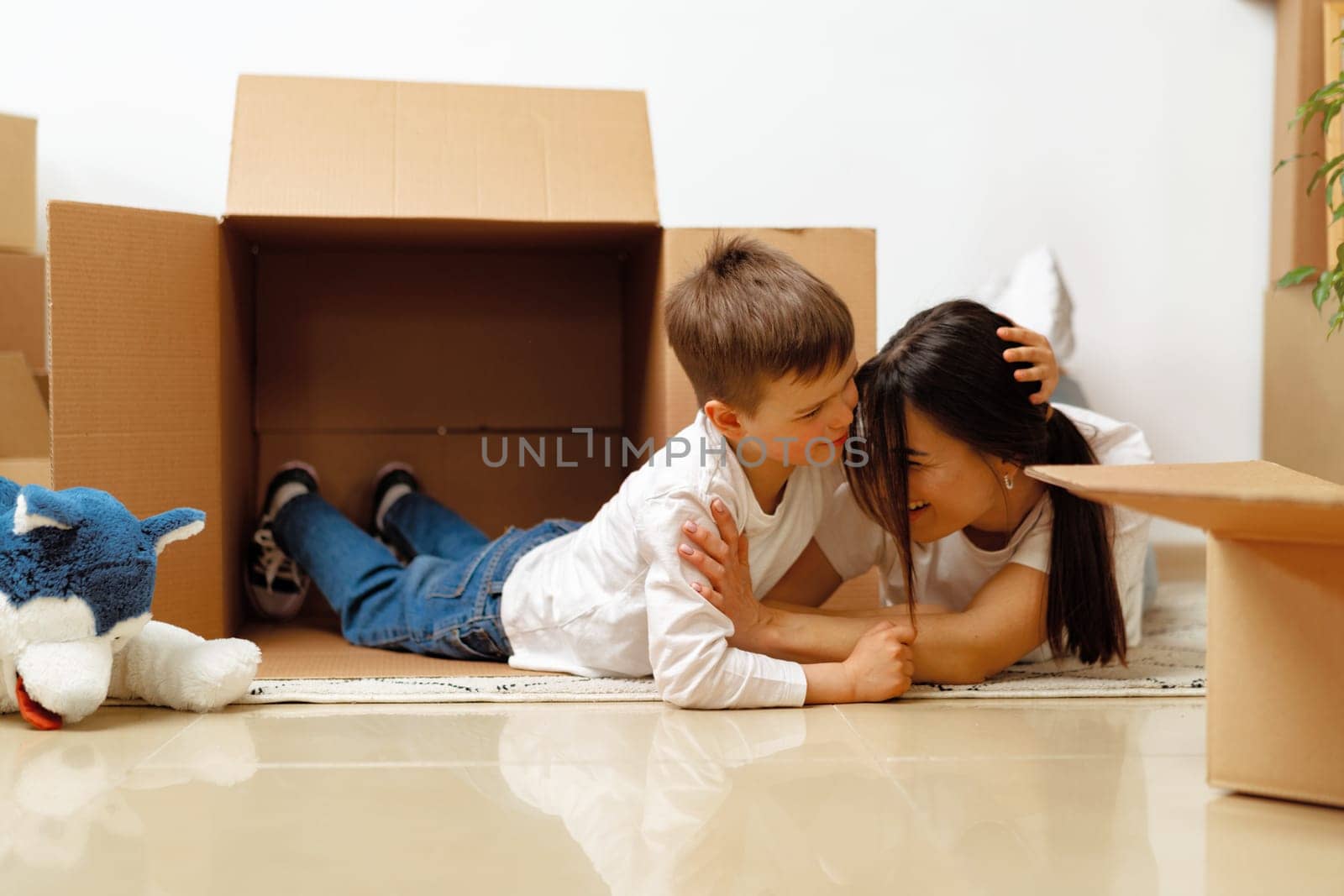 Beautiful smiling woman and little boy with cardboard boxes moving to new home, close up