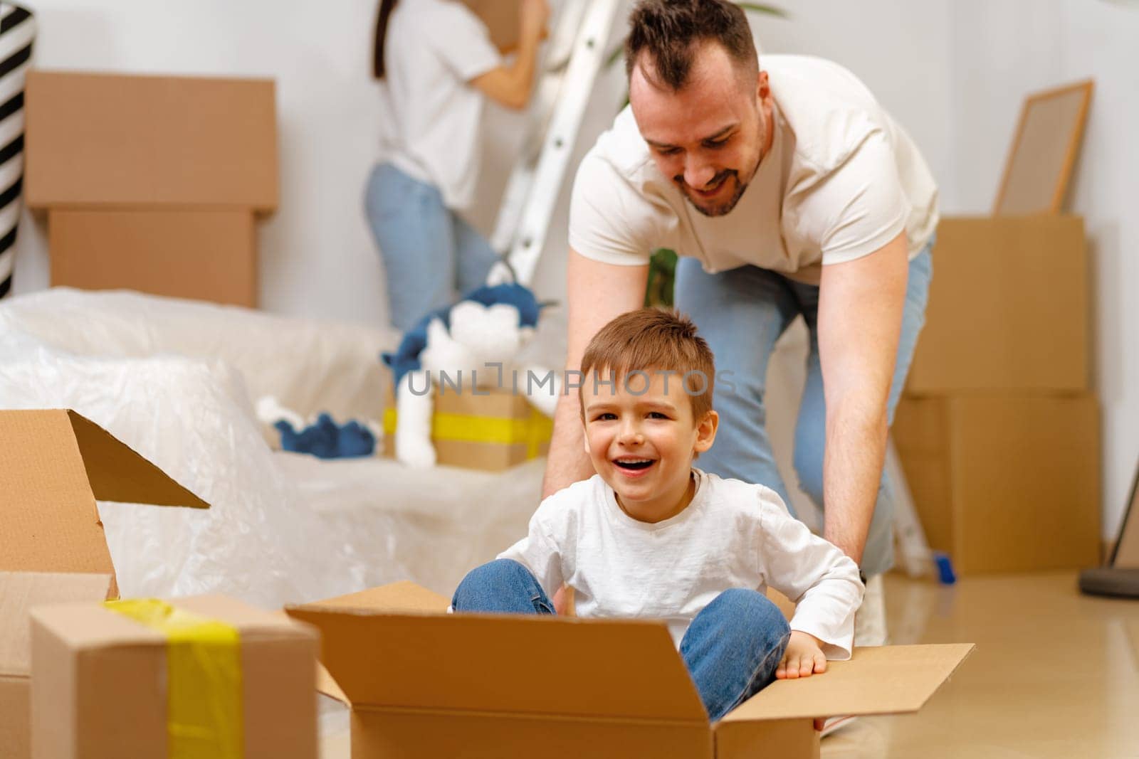 Parents and son packing boxes and moving into a new home by Fabrikasimf