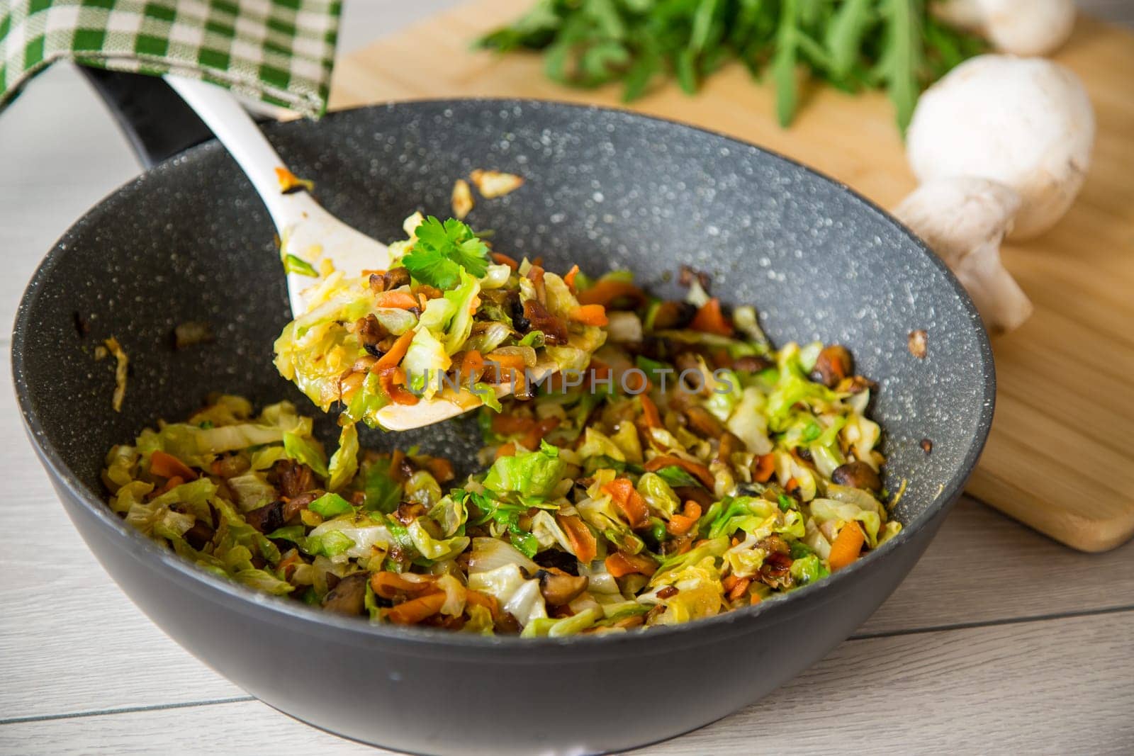 cabbage early fried with mushrooms, carrots and vegetables in a frying pan.