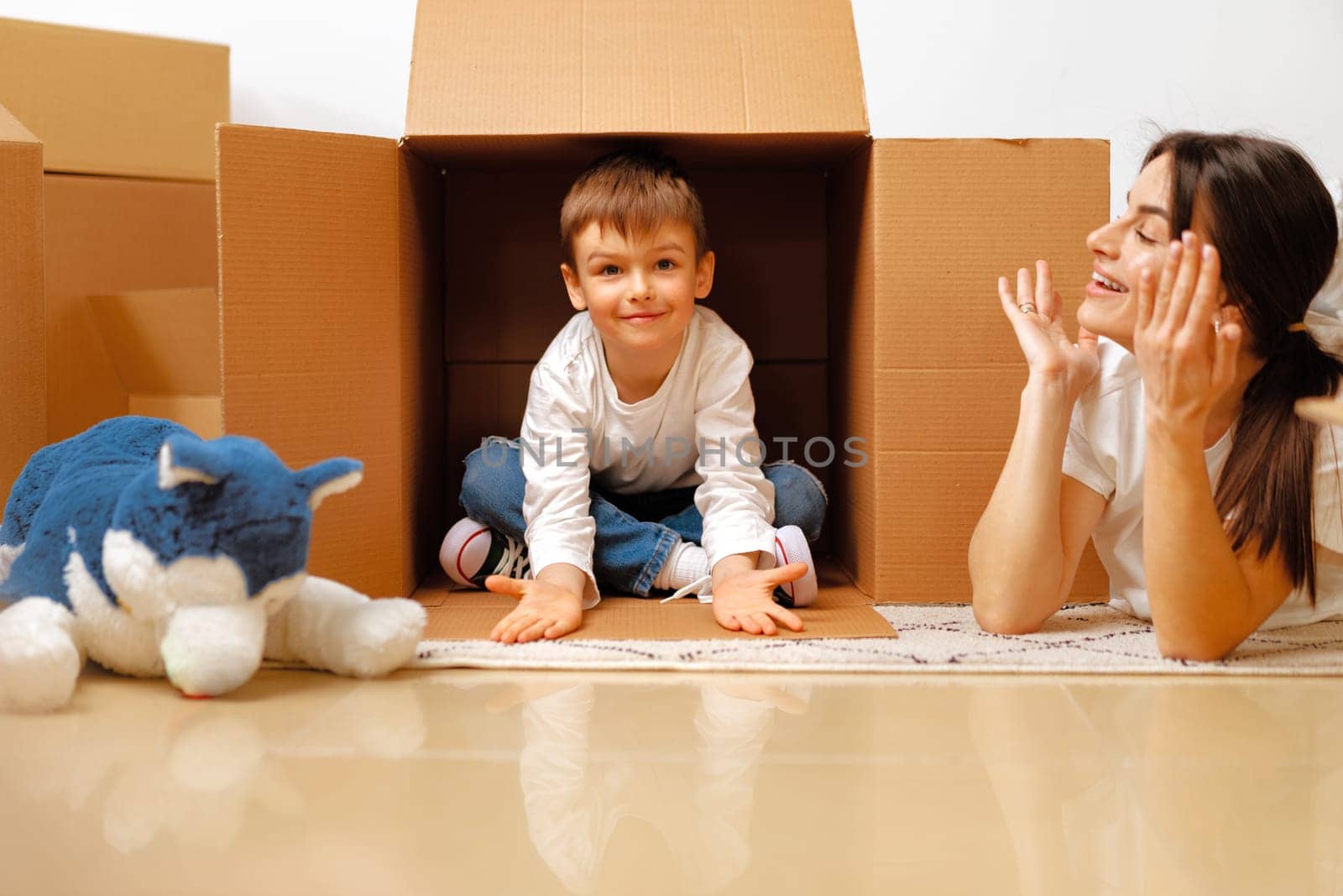 Beautiful smiling woman and little boy with cardboard boxes moving to new home by Fabrikasimf