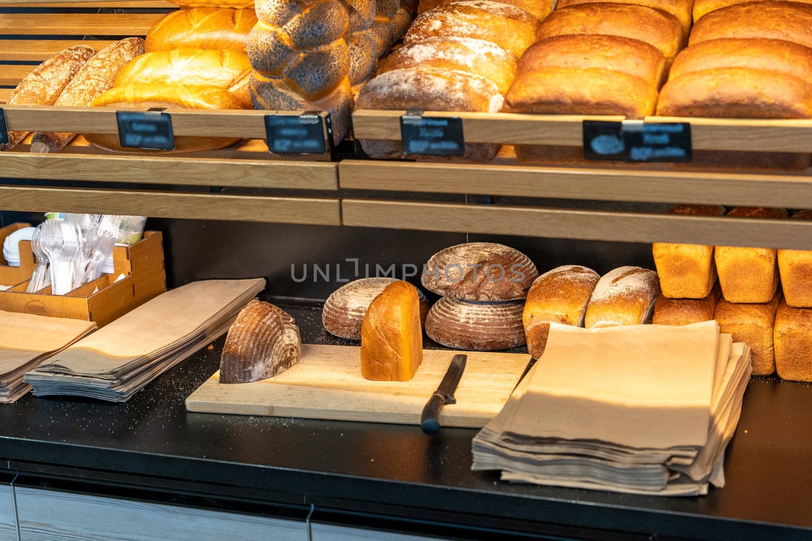 bread and rolls on the shelves of the bread shop. A modern bakery with various types of bread. breads shelves. Bread and fresh pastries wood showcase, bakery products in wooden interior