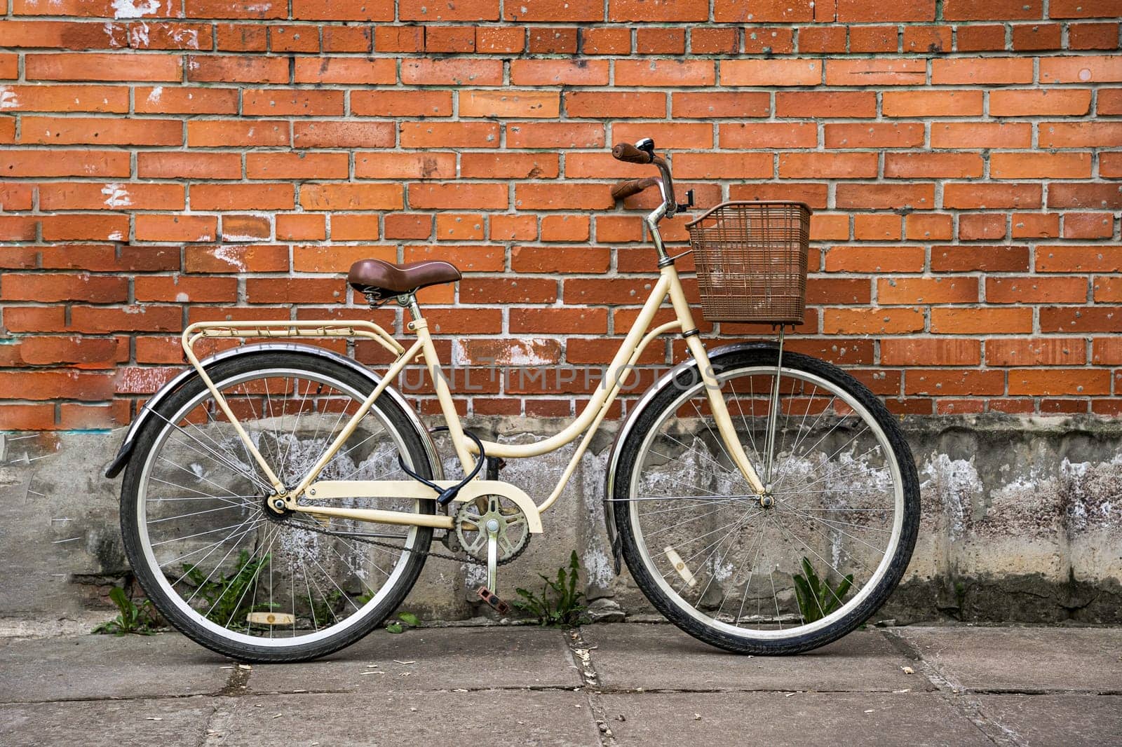 a lady's city bike with a basket leaning against the brick wall of the building. environmentally friendly transport. Vintage