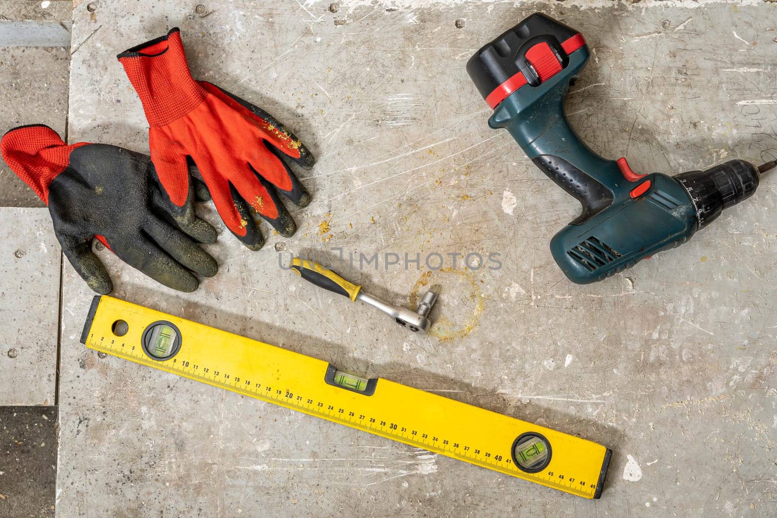 Construction tools on the table. cordless screwdriver, ruler, screws, work protective gloves, wrench, construction level. top view