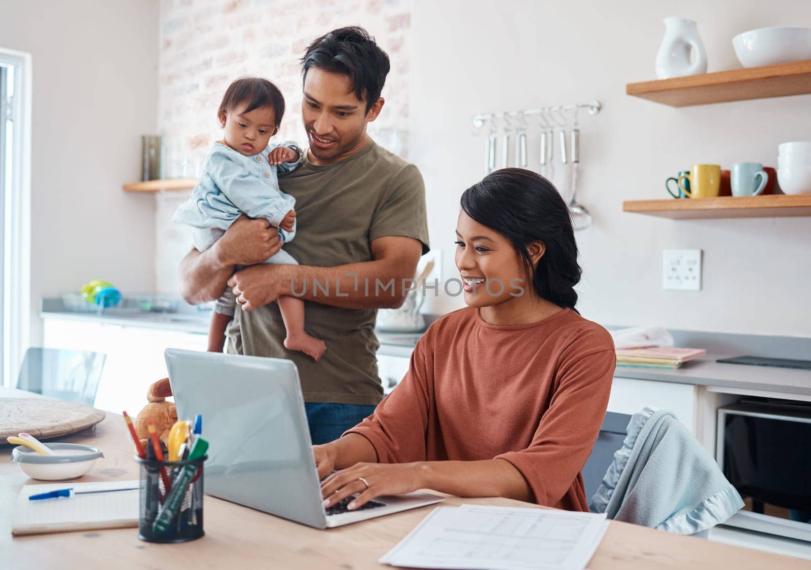 Internet, family and parents doing research on down syndrome with baby on a laptop in their house. Mother and father with smile for child and working on taxes or finance budget on the computer by YuriArcurs