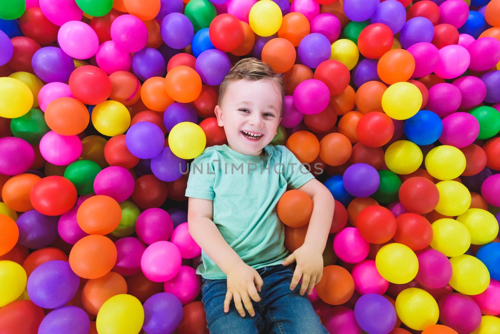 Happy child playing and having fun in kindergarten with colorful balls.