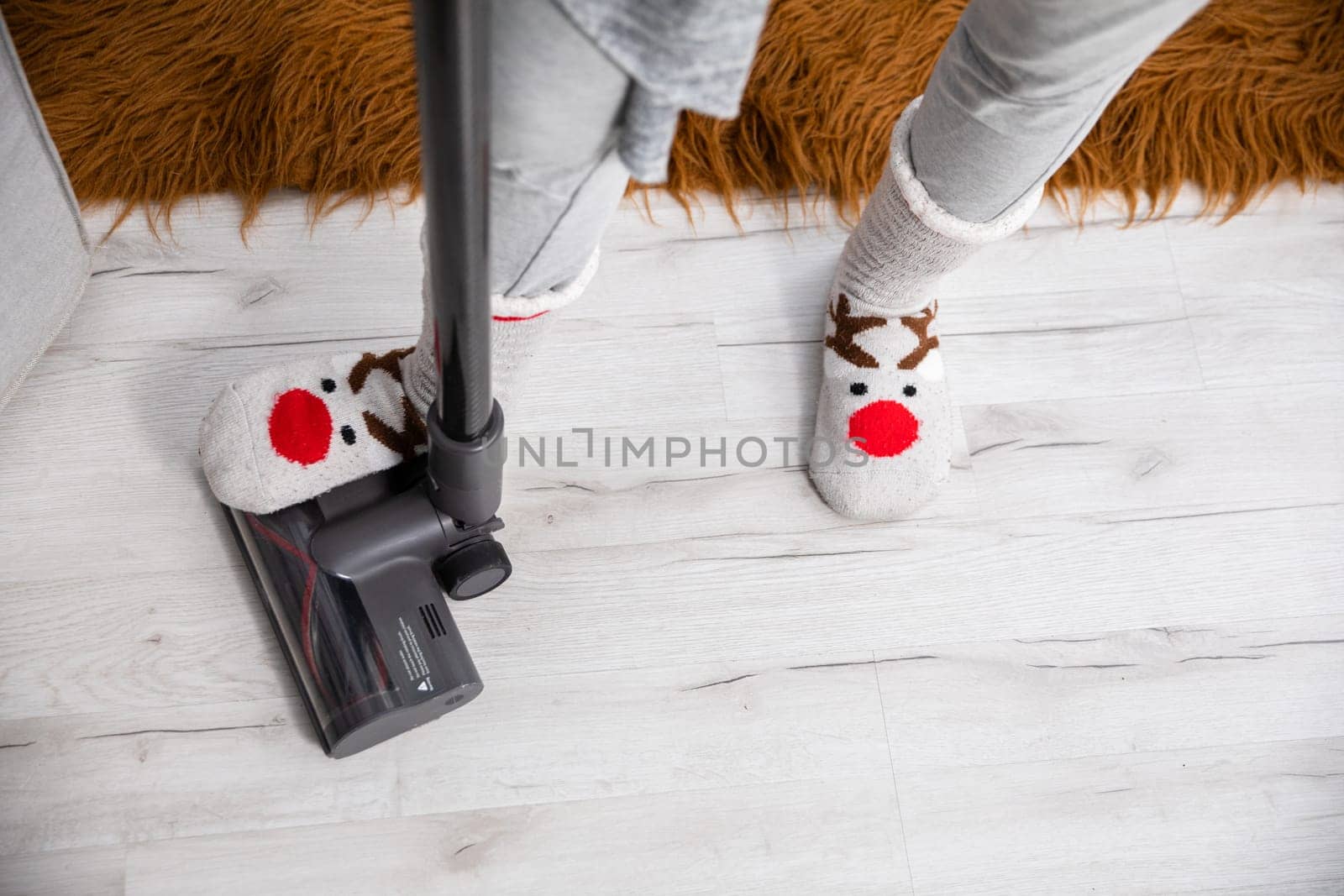 An overhead view of a foot trampling a vacuum cleaner tip. Keeping things tidy by frequently cleaning the floorboards.