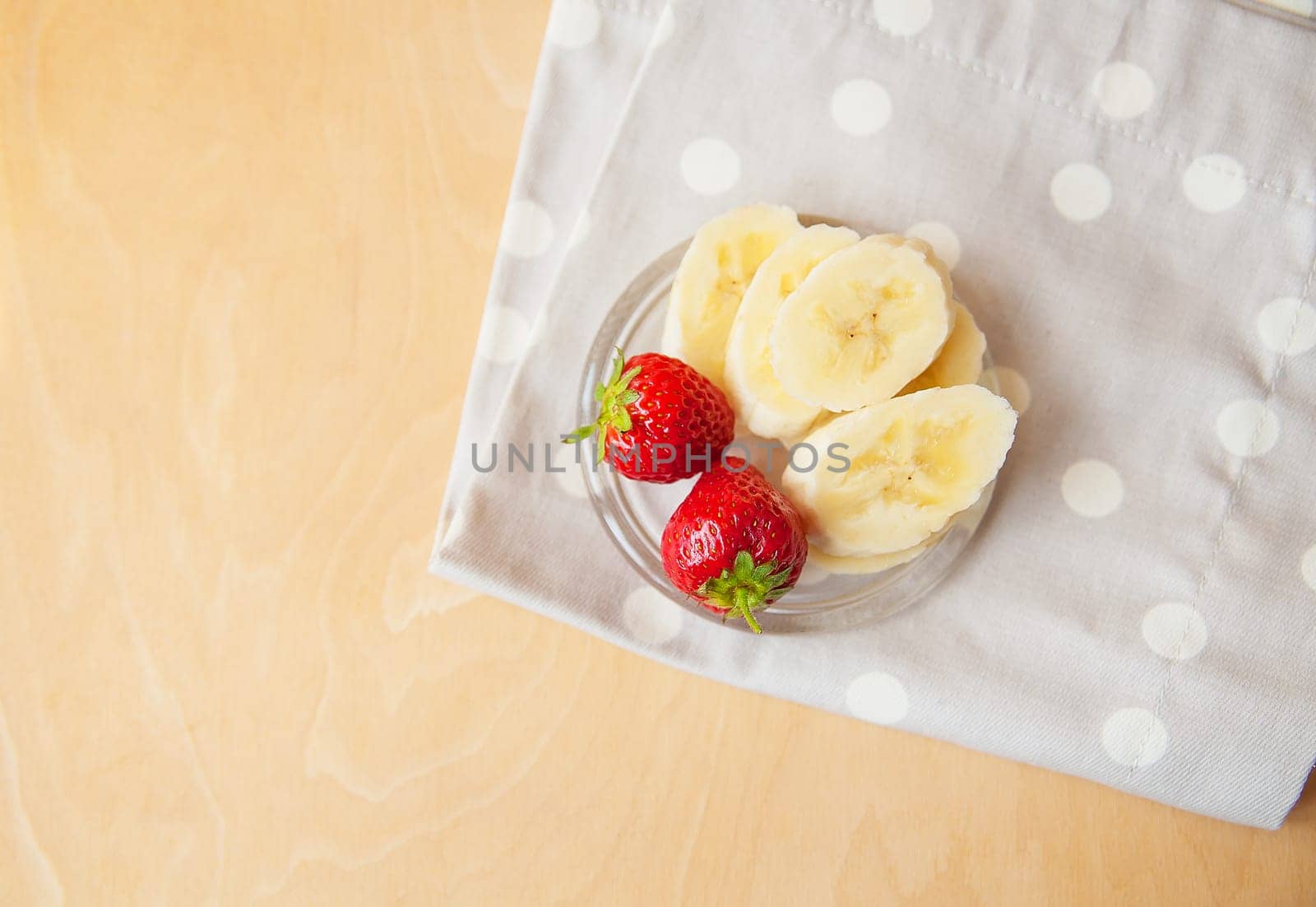 strawberry and banana on a glass plate on a wooden background