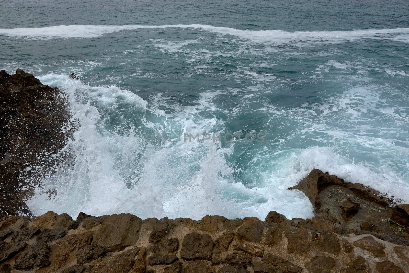 Waves breaking on the shore on a pebble road. water foam, wild waters, texture, ocean, sea, rocks,danger
