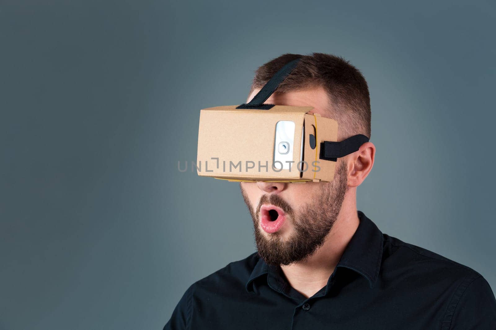 Man using a new virtual reality headset on grey background. Men's emotions