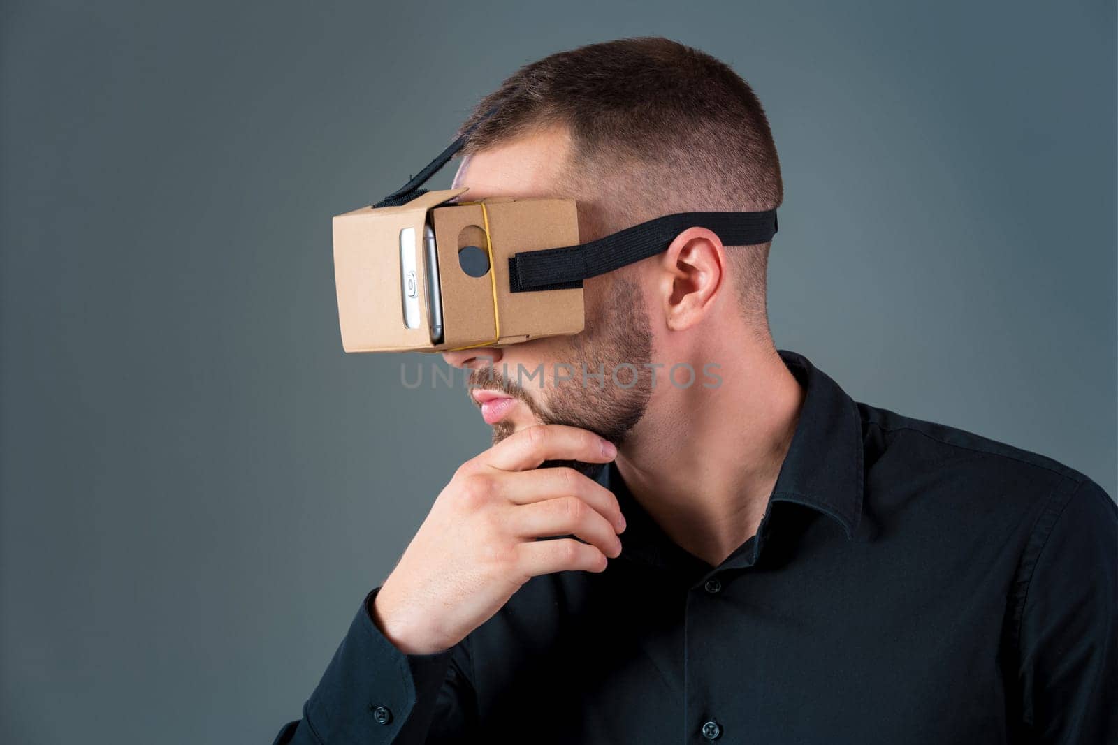Man using a new virtual reality headset on grey background. Men's emotions