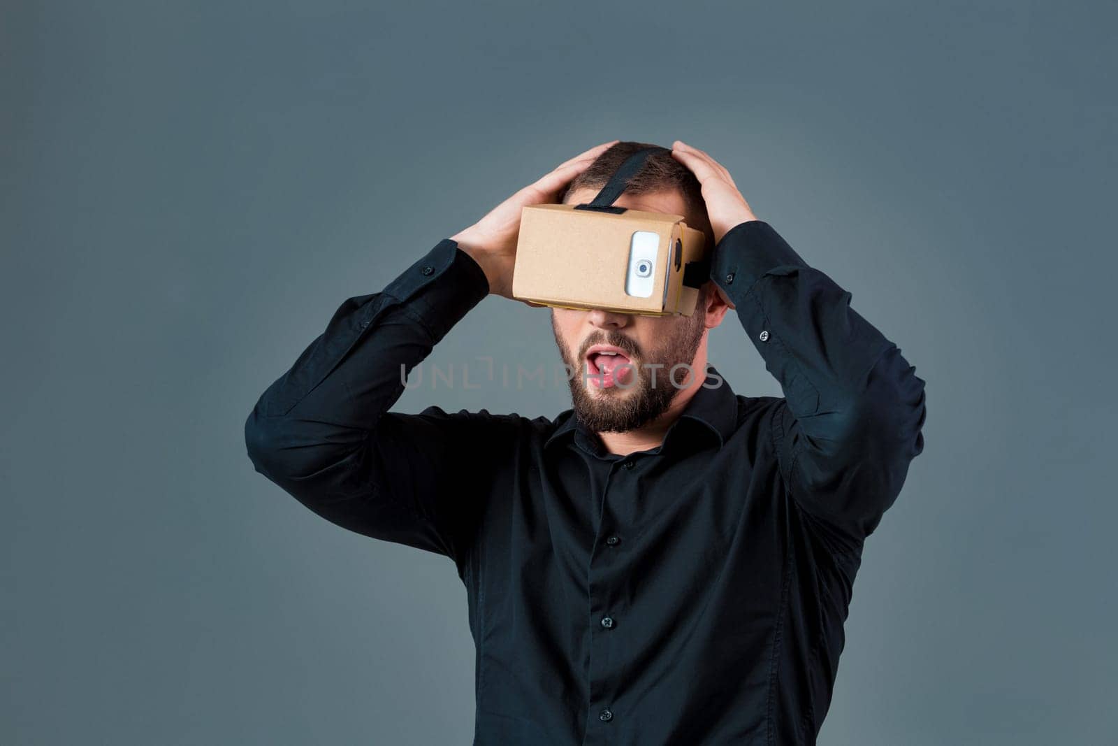 Man using a new virtual reality headset on grey background. Men's emotions