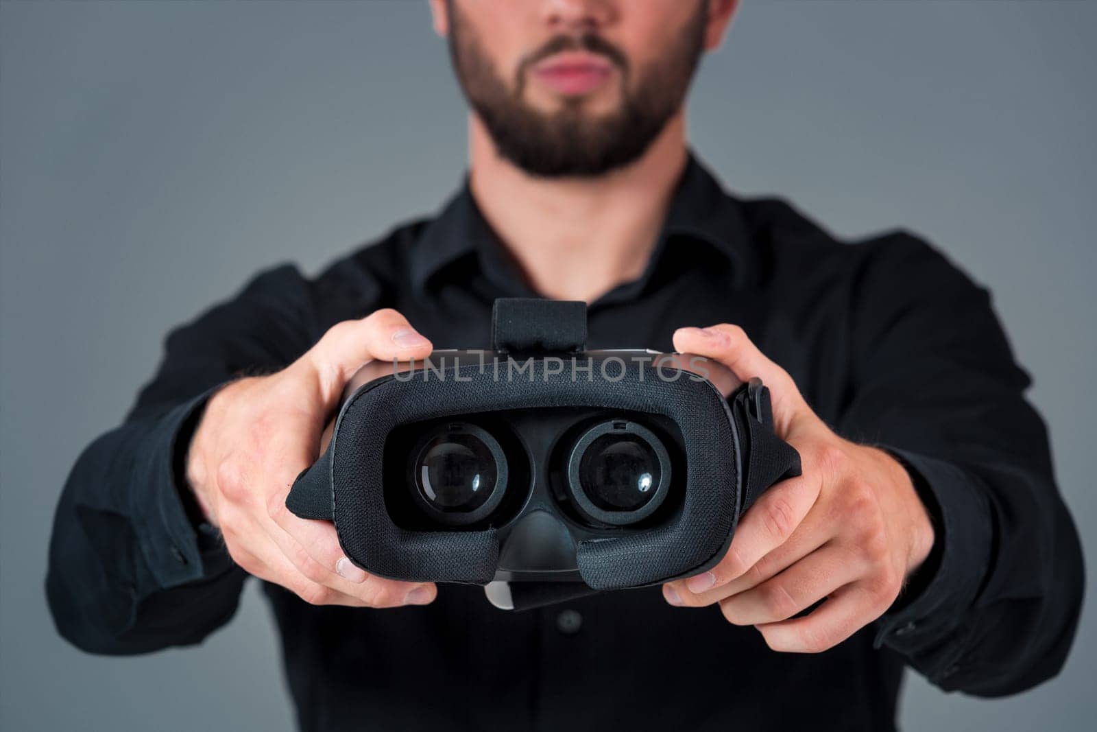 Man offers to wear glasses virtual reality, VR goggles, VR-headset glasses. A man on a gray background