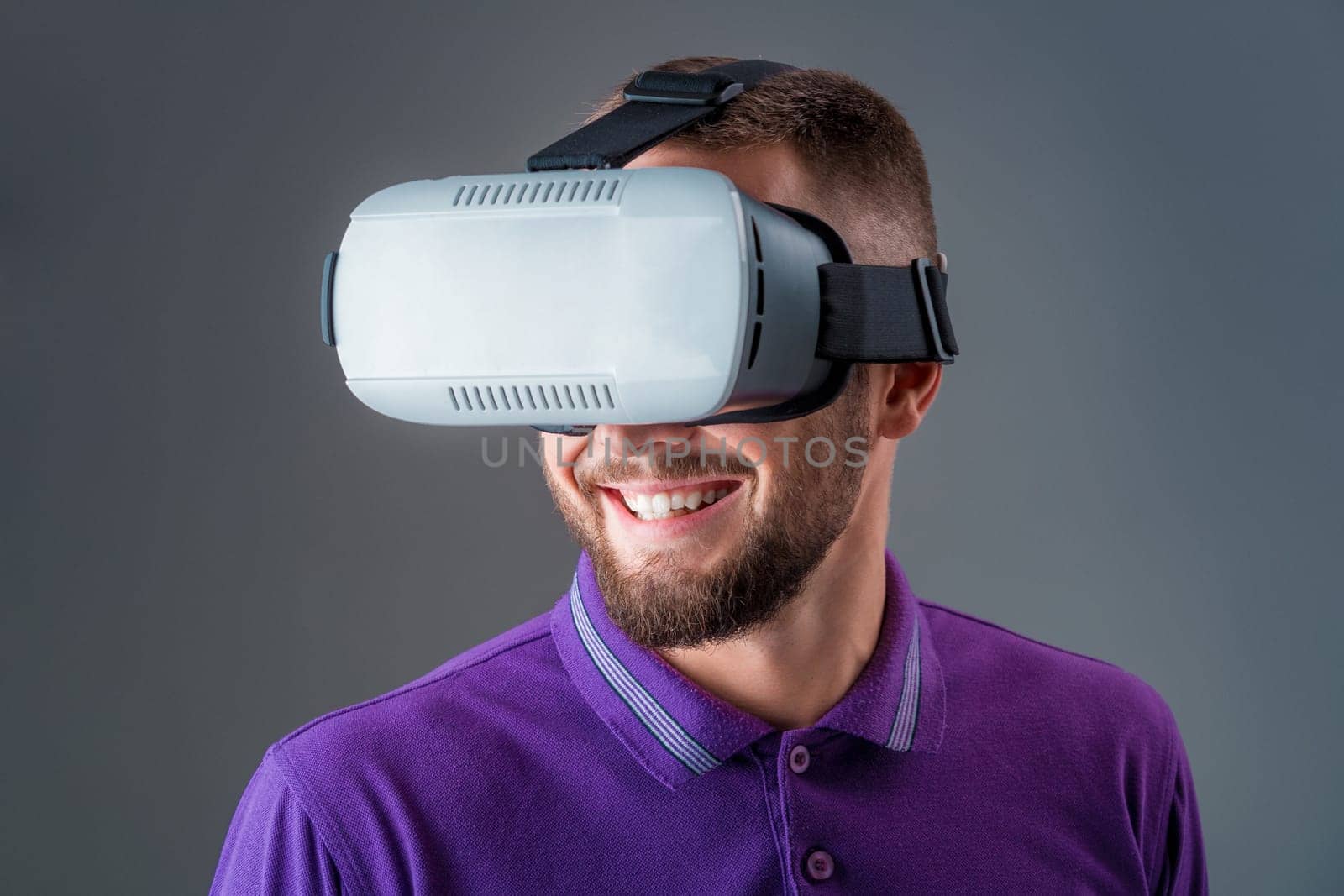 Man in studio wearing virtual reality headset playing game. Man dressed in a purple T-shirt