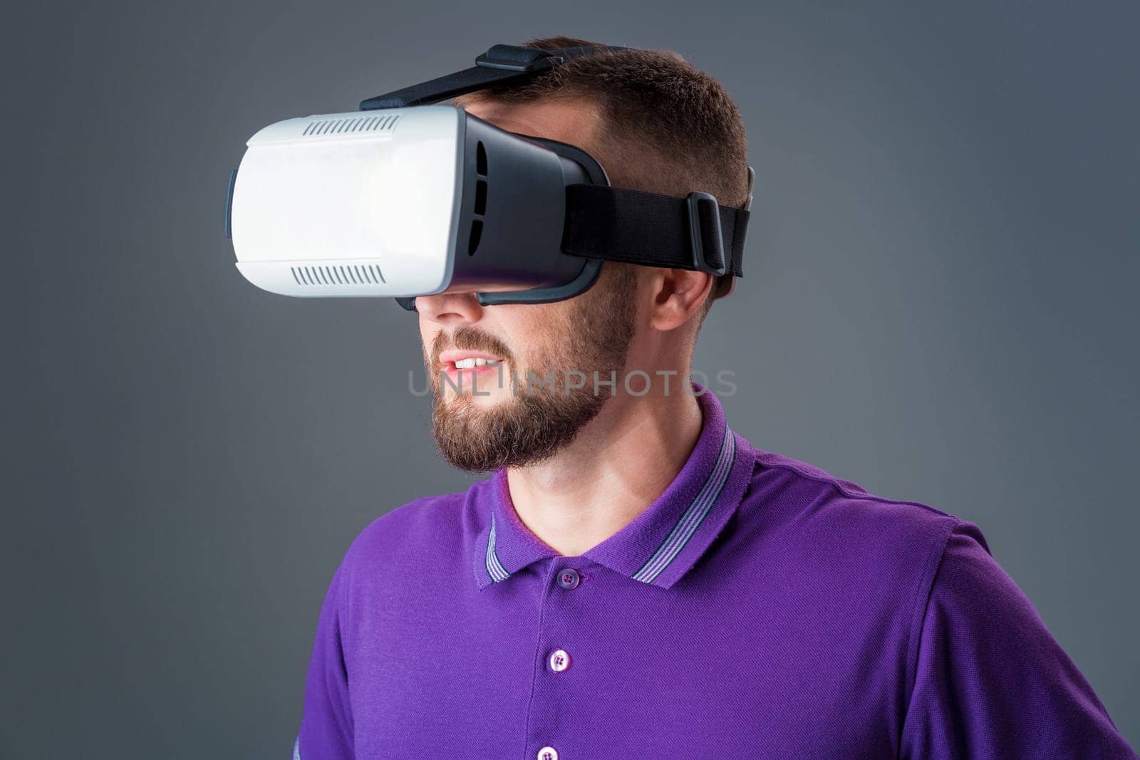 Man in studio wearing virtual reality headset playing game. Man dressed in a purple T-shirt