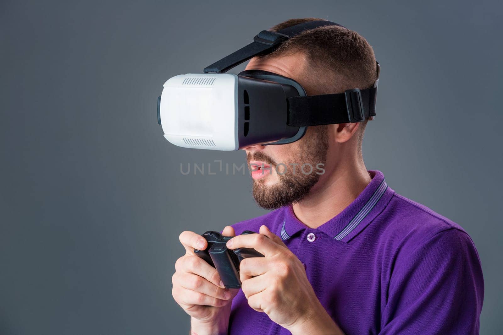 Man in studio wearing virtual reality headset playing game. Man dressed in a purple T-shirt