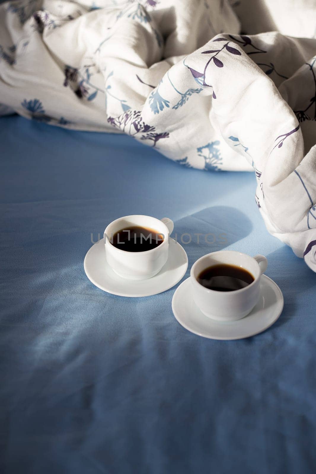 Two white cups of coffee are in bed, sunny morning by sfinks