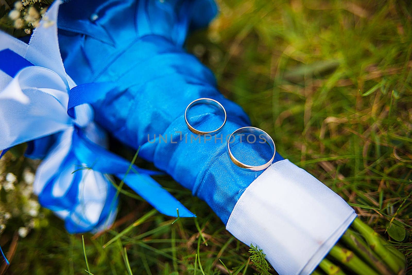 wedding rings and bridal bouquet lying on a green grass