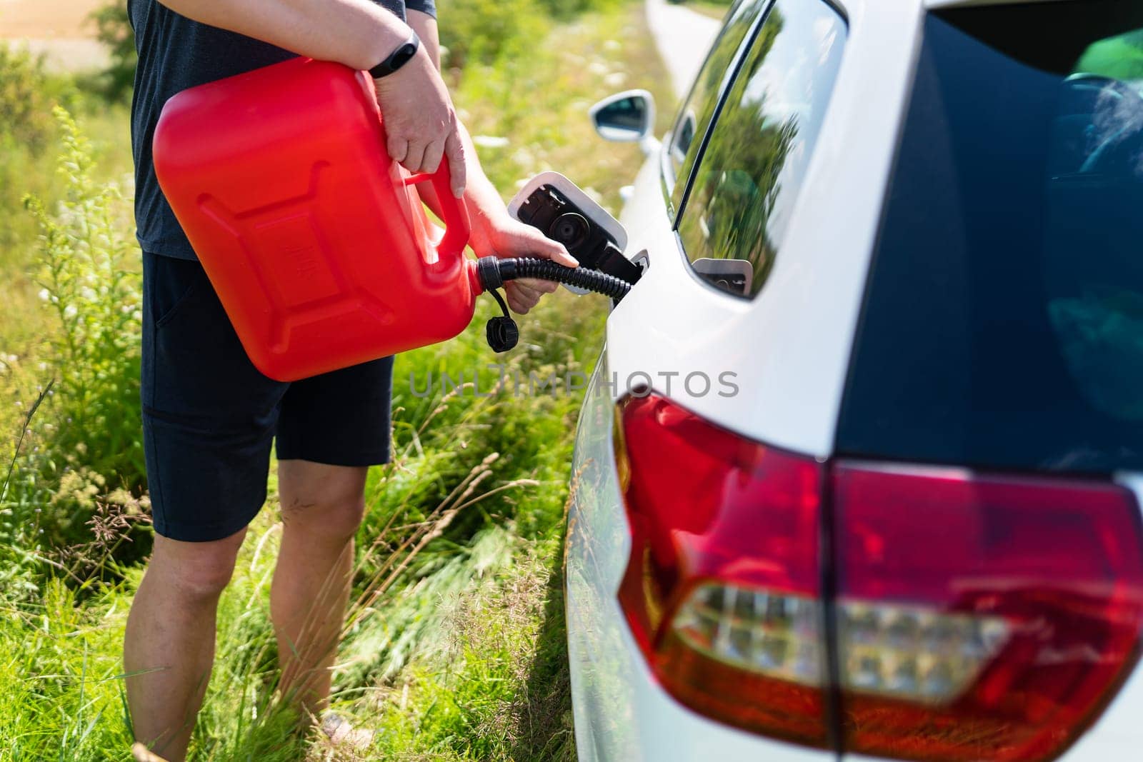 The car parked on the side of the road, the driver refuels the car from the canister. Help on the road. Lack of fuel - oil, diesel, gasoline