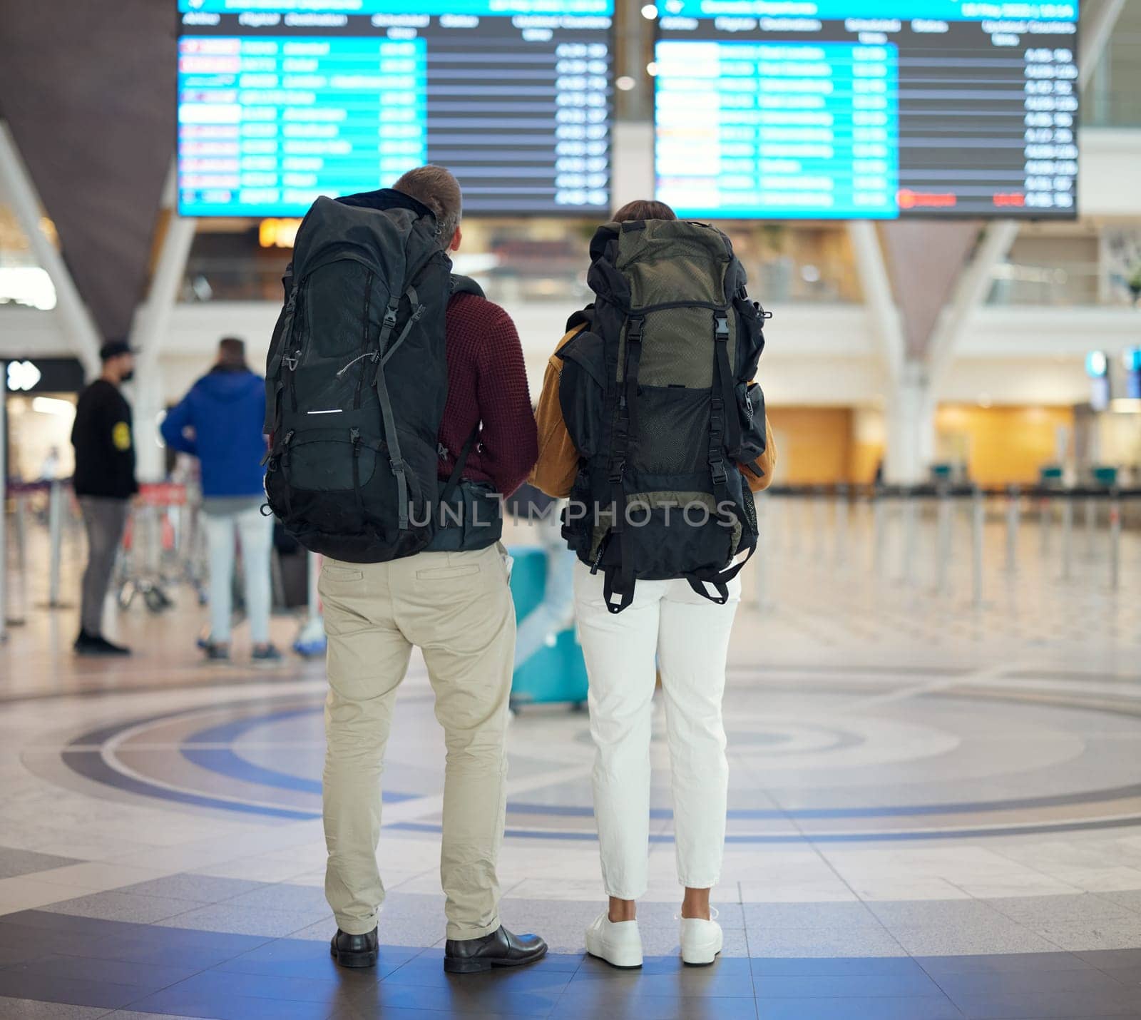 Couple, airport and reading on board, schedule and screen for flight on travel, plane or adventure with back. Man, woman and global immigration in lobby for airplane time, departure or transportation.