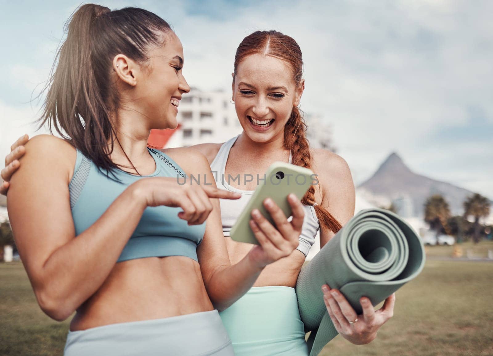 Yoga, fitness and social media with woman friends in the park together for mental health exercise. Exercise, phone and training with a female and friend outside on a grass field for a summer workout by YuriArcurs