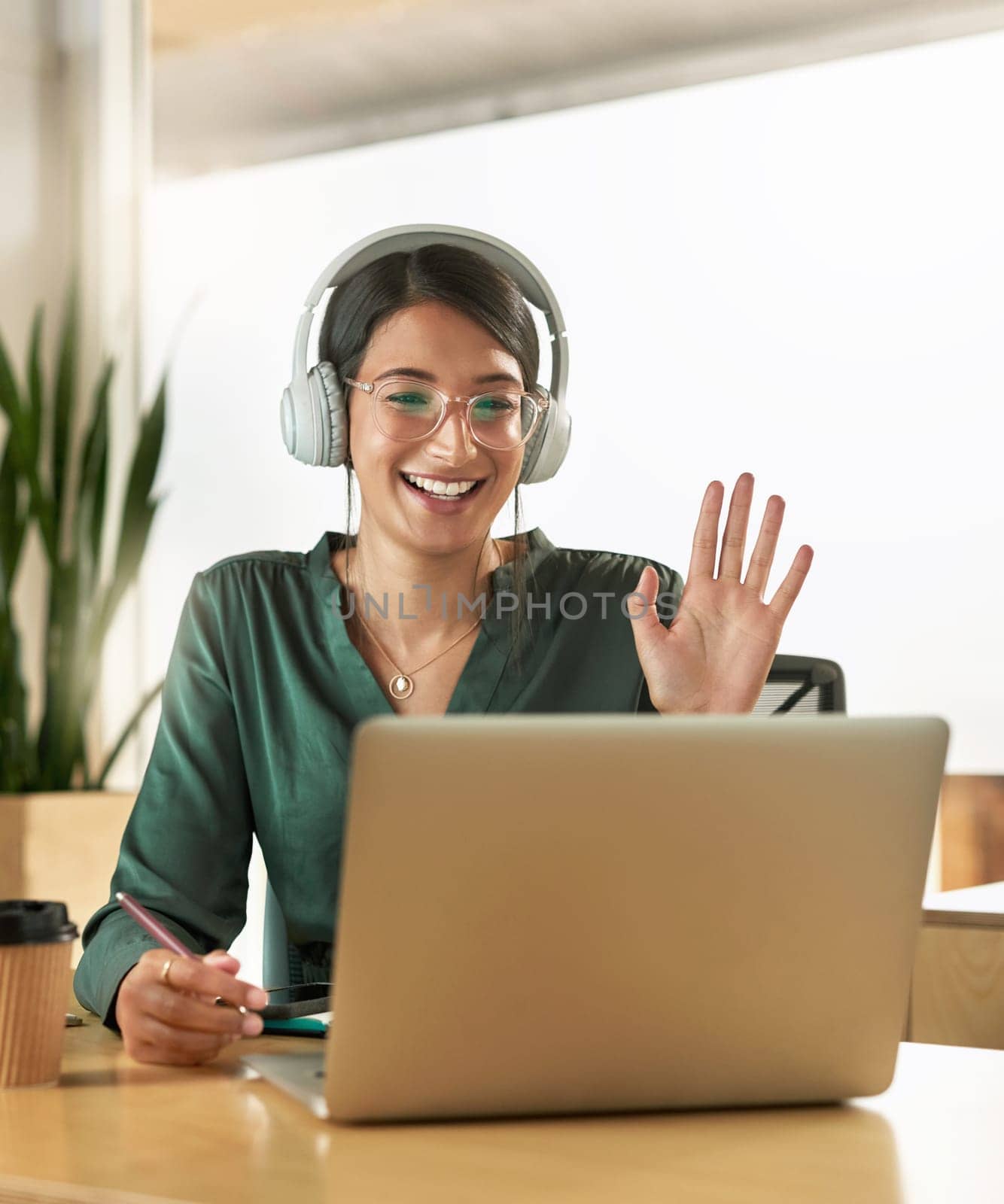 Virtual meeting, business woman and wave on a video call with headphones and greeting. Laptop, working and female employee with webinar at a company with computer and digital communication at office.