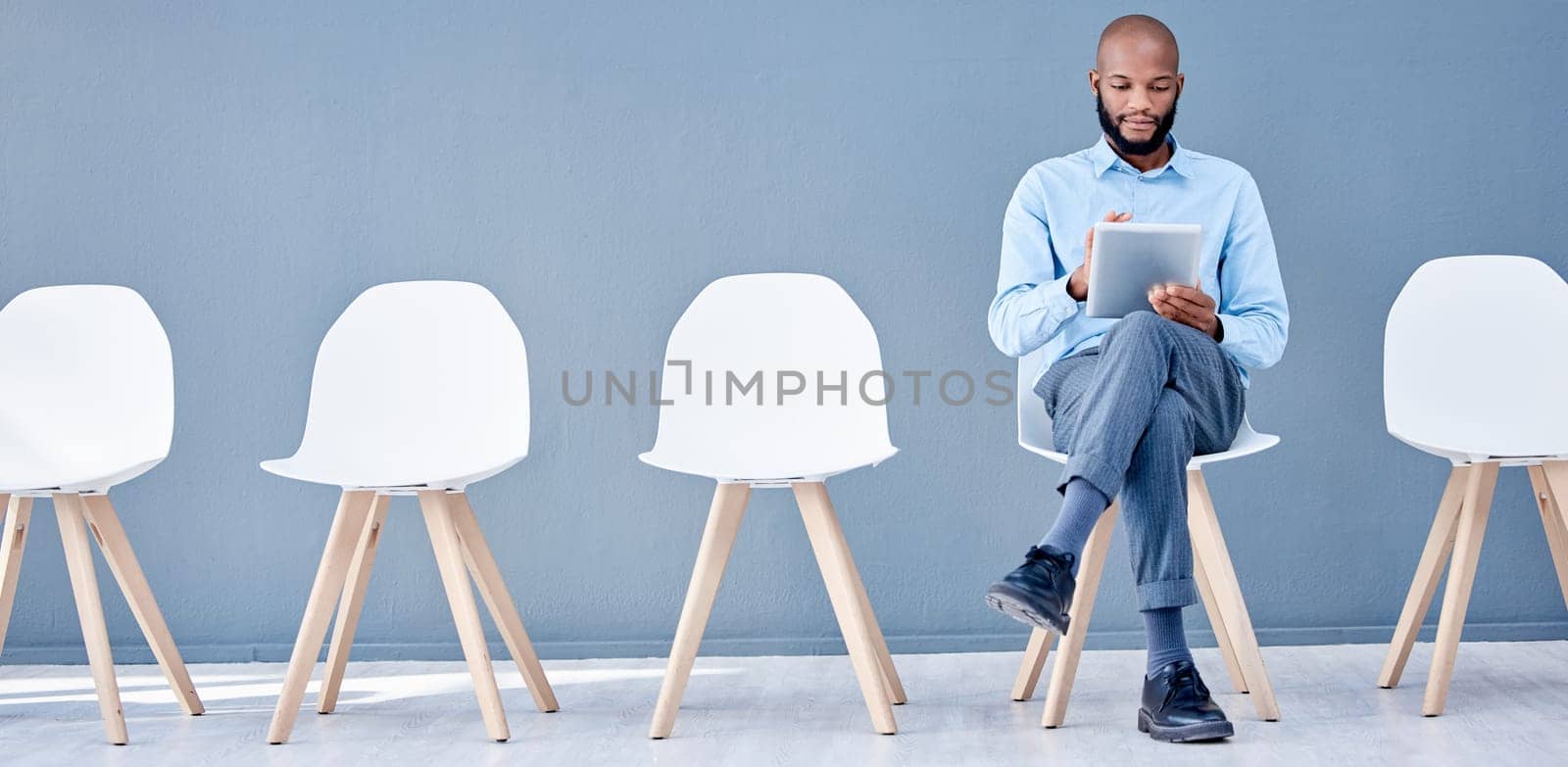 Waiting room, tablet and black man sitting at job opportunity, career application or Human Resources interview. Professional person or worker search online website for hr recruitment or hiring email.