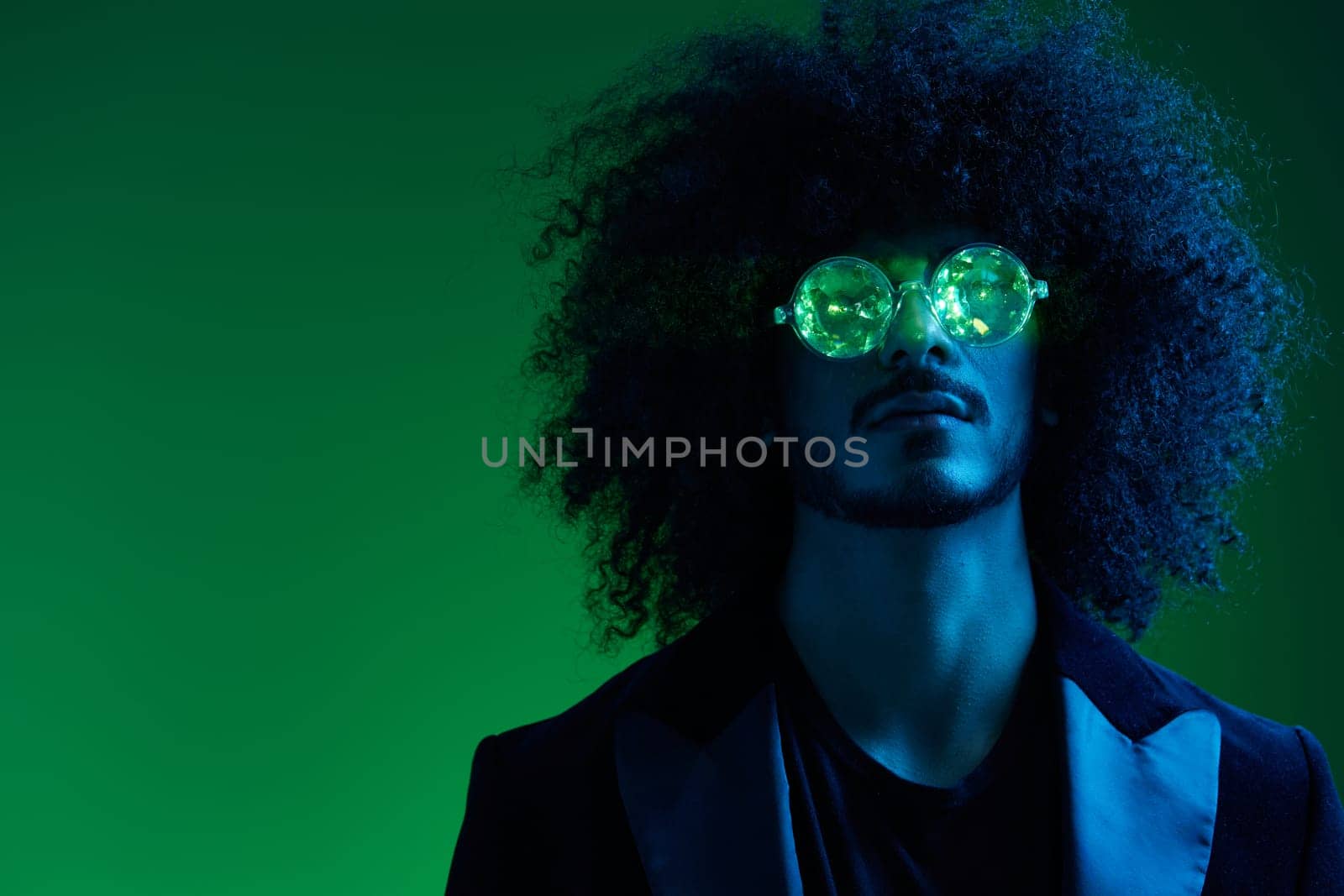 Fashion portrait of a man with curly hair on a green background with sunglasses, multinational, colored pink light, trendy, modern concept. by SHOTPRIME