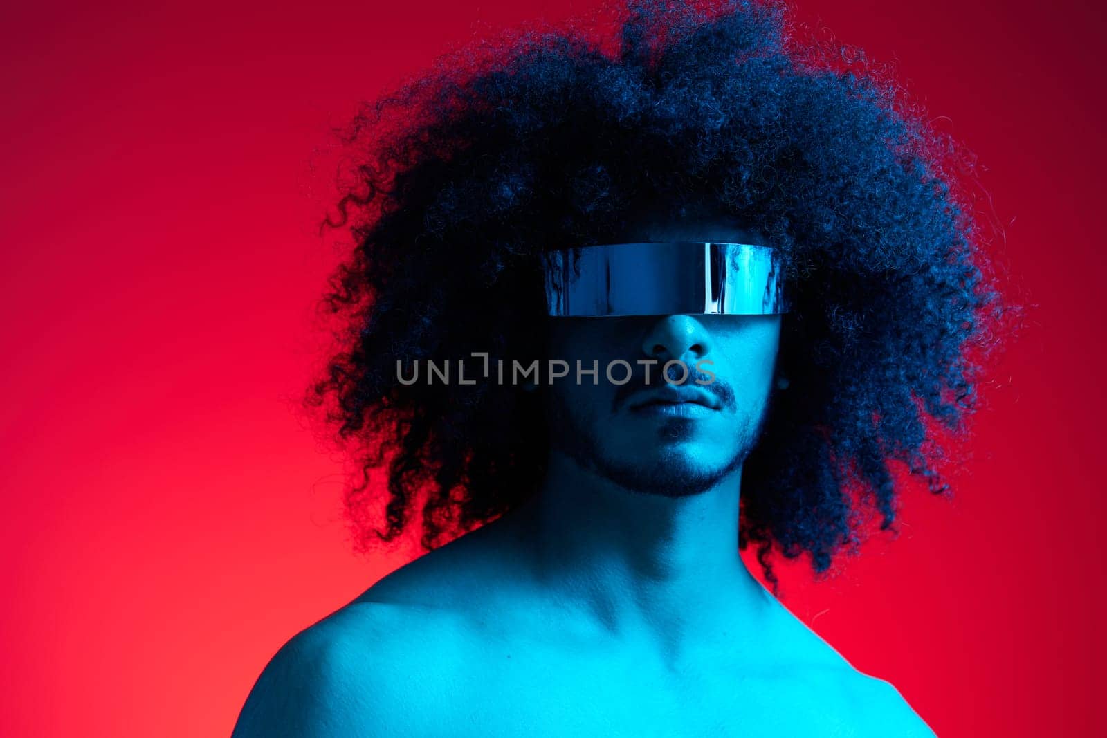 Portrait of fashion man with curly hair on red background with stylish glasses, multinational, colored light, black leather jacket trend, modern concept, sexy body. by SHOTPRIME