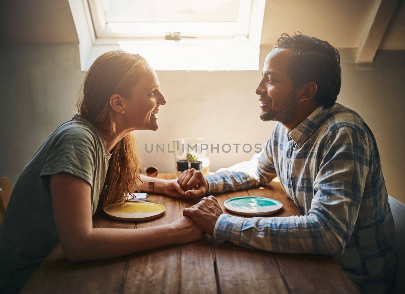 Love, couple and holding hands at home on table, talking and bonding together. Valentines day, romance diversity and affection of man and woman on date, having fun and enjoying quality time in house