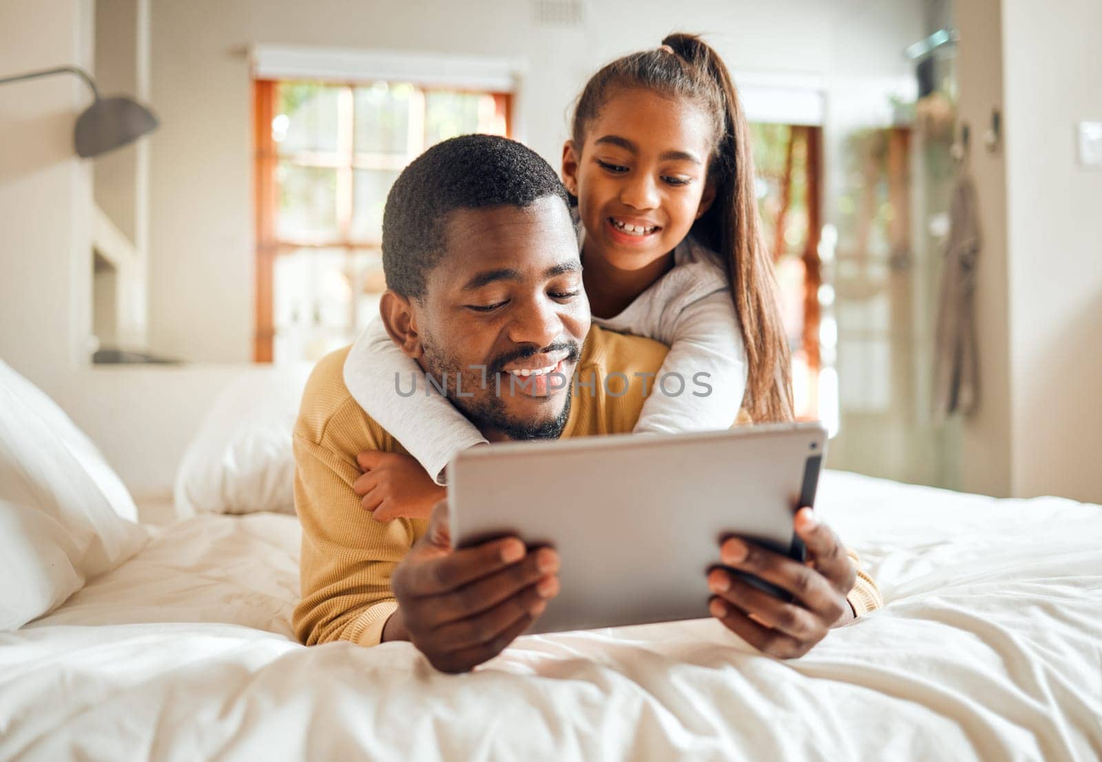 Black family, tablet or education with a father and daughter lying together on a bed in their home for learning. Relax, internet and kids with a man and girl in a bedroom for growth or development by YuriArcurs