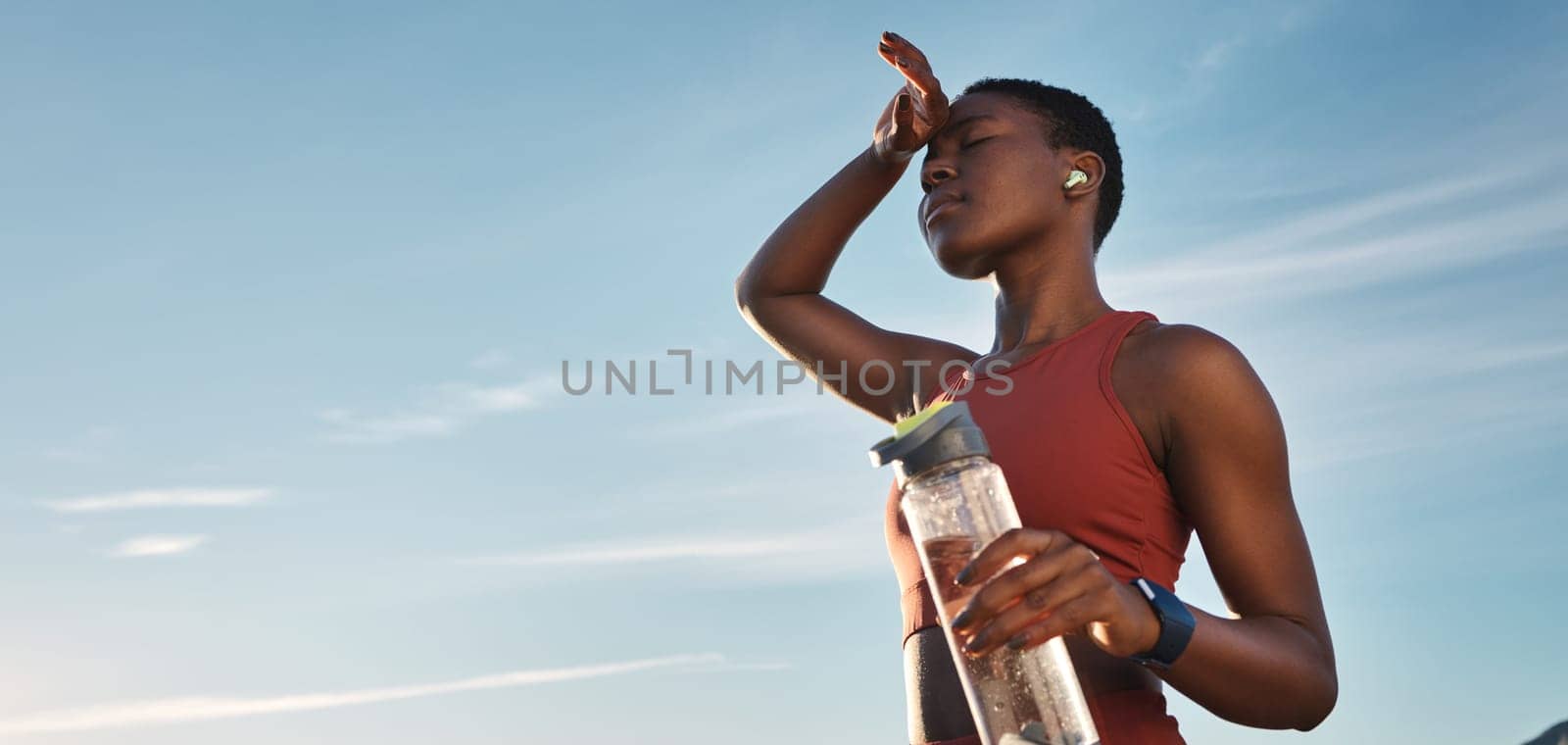 Water bottle, tired and black woman on break after running, exercise or cardio workout with low angle and mock up. Sports, fitness and sweating female holding liquid for hydration after training