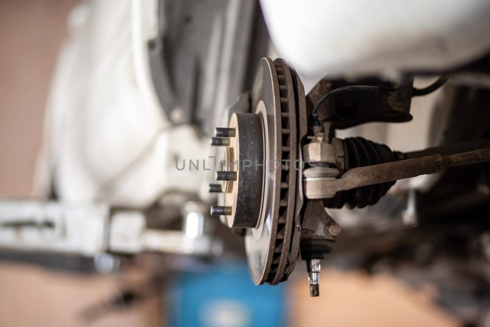 Disc brake of the vehicle for repair, in process of new tire replacement. Car brake repairing in garage.Suspension of car for maintenance brakes and shock absorber systems. Replacement of brake pads.