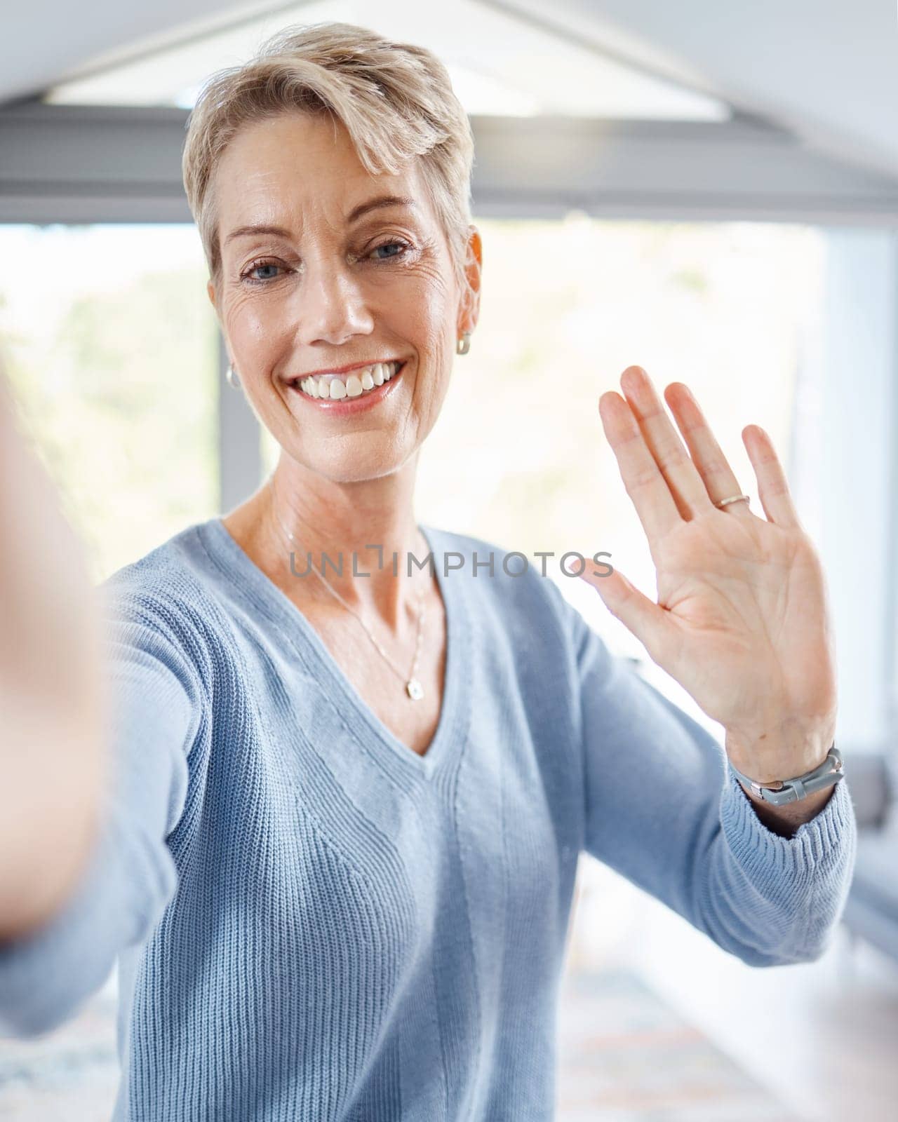 Portrait, senior woman and wave for video call, communication and social media. Mature female, hand gesture and greeting with smile, hello or goodbye for connection, recording or facetime for talking by YuriArcurs