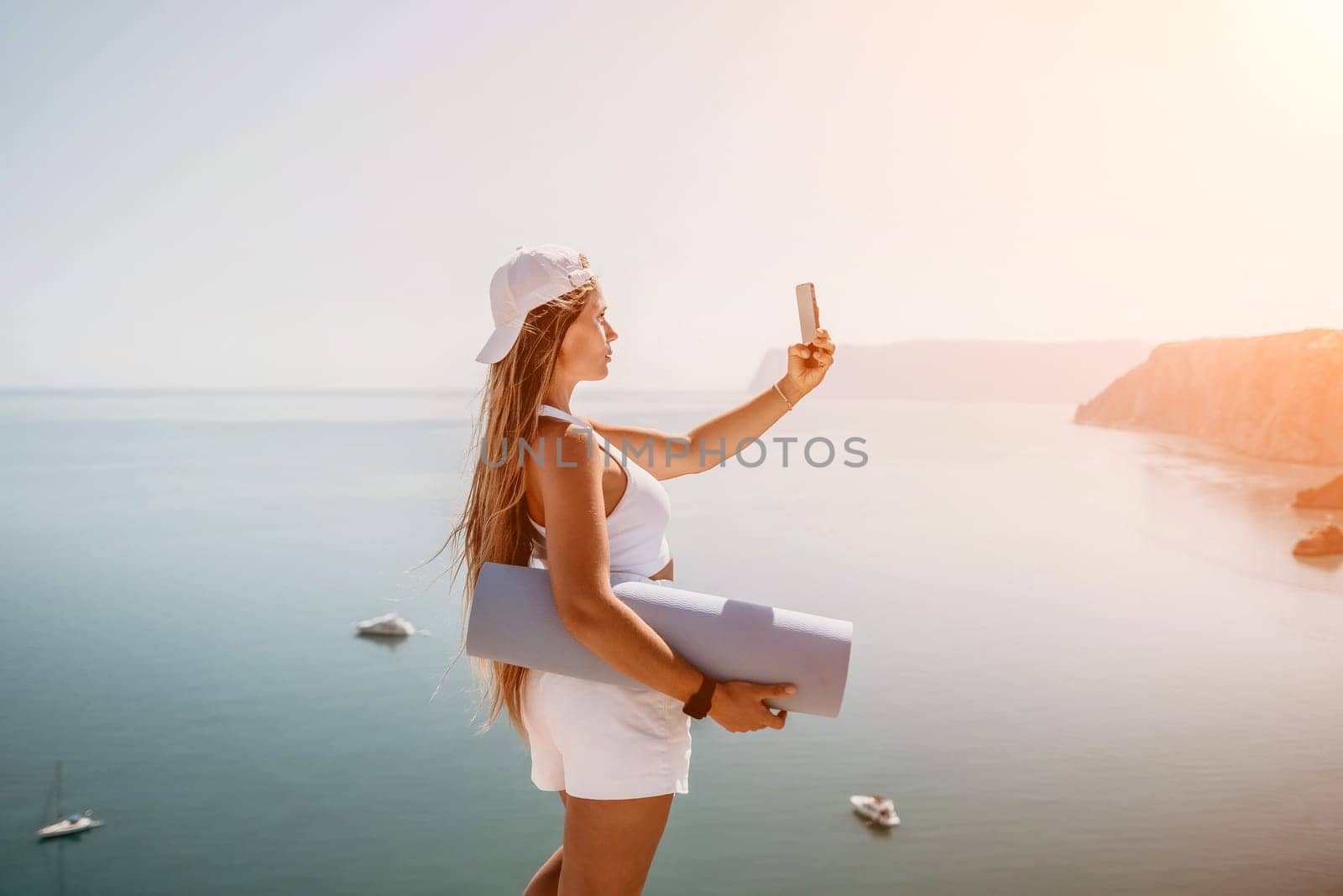 Young woman with black hair, fitness instructor in pink sports leggings and tops, doing pilates on yoga mat with magic pilates ring by the sea on the beach. Female fitness daily yoga concept