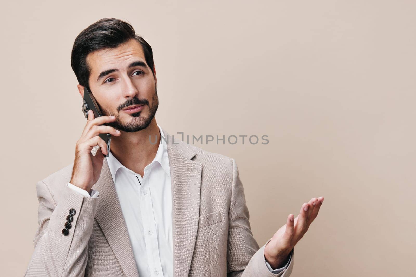 studio man phone young portrait entrepreneur communication smile smartphone blogger hold happy online suit isolated call beard handsome business app technology