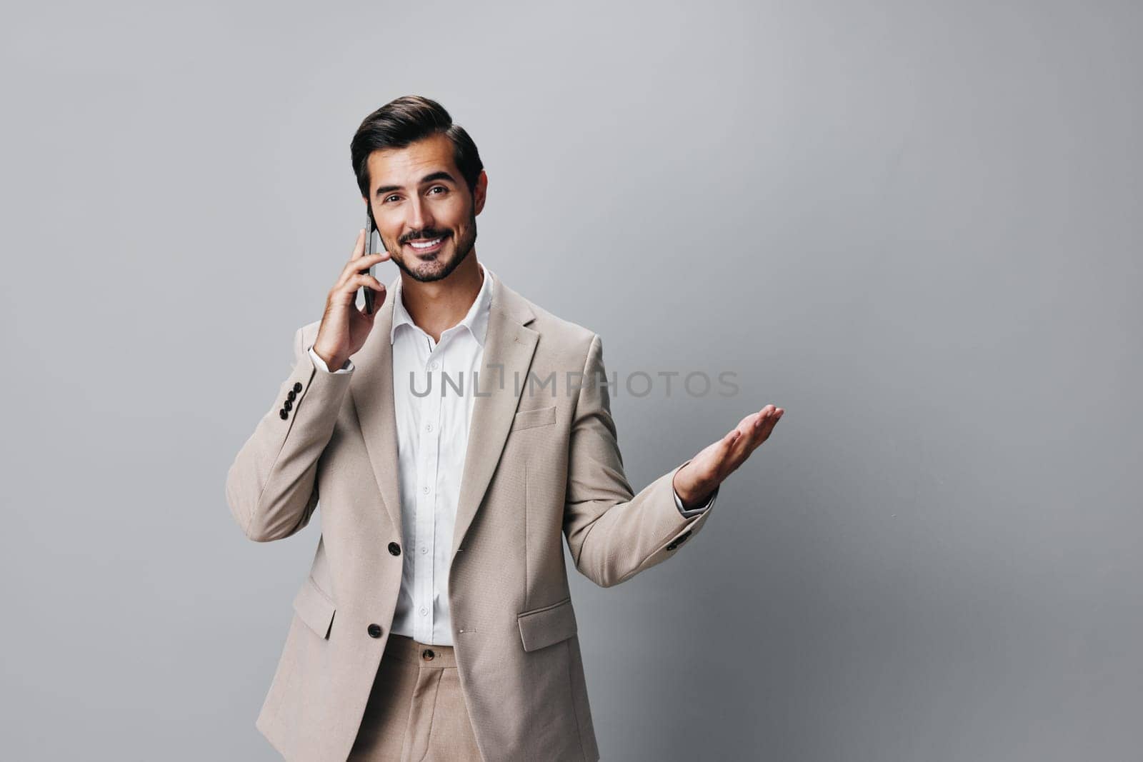 cell man background studio holding adult corporate smile lifestyle suit business smartphone guy message beige phone call hold male white happy portrait