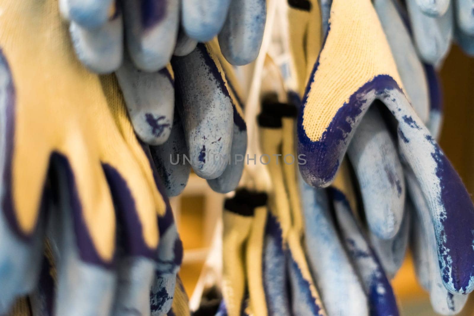 Rubberized grey work gloves hanging on the wall. Part of work-wear and protection equipment. by Zelenin