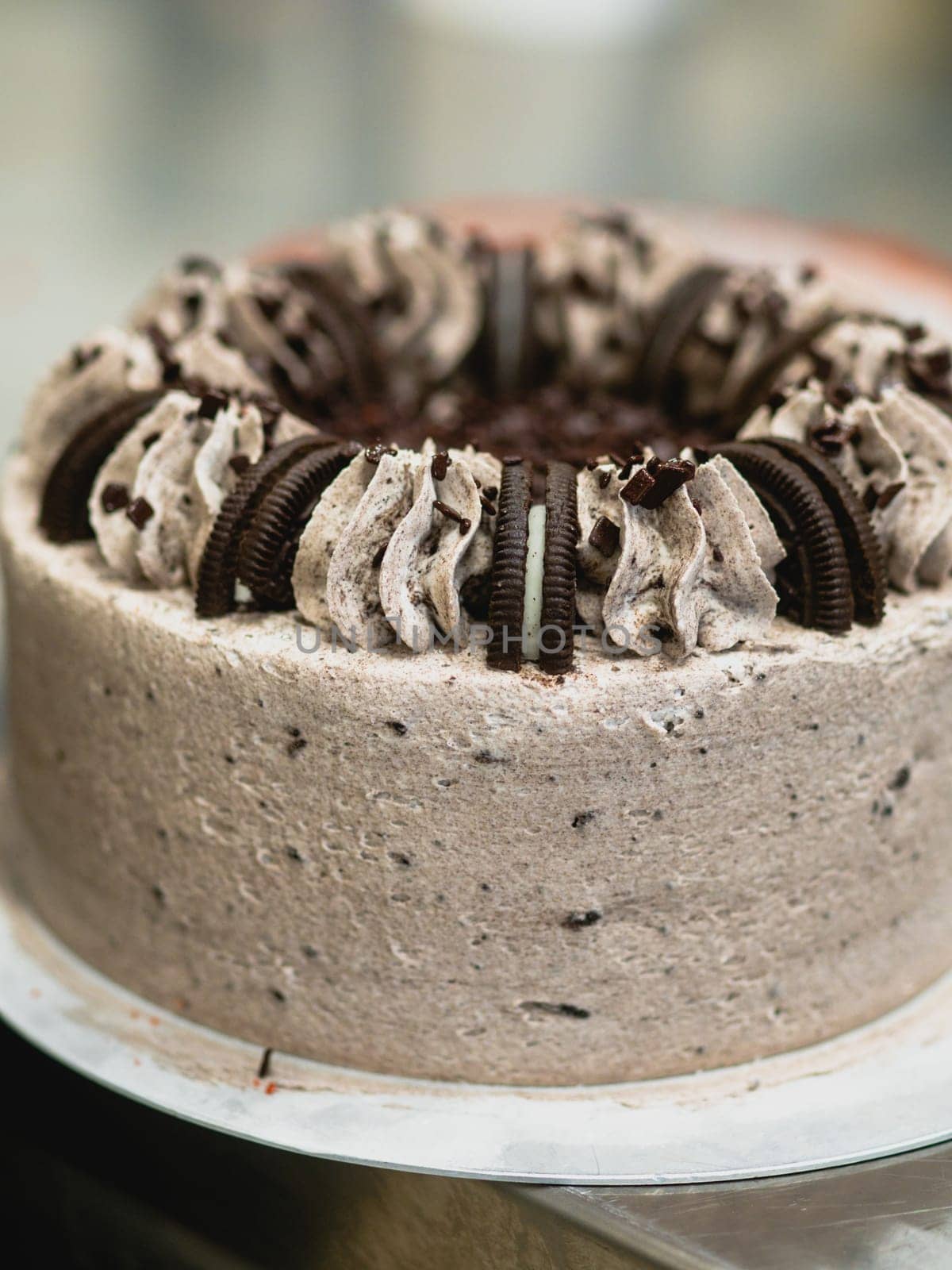 preparing brown frosted icing cup cake with cookies on top in the kitchen
