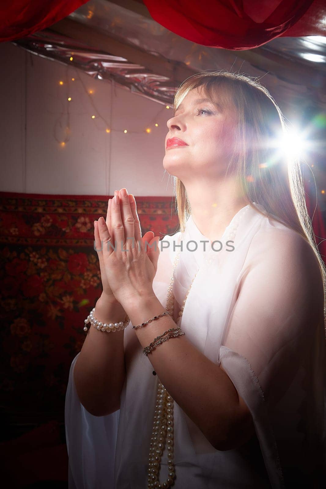 Beautiful European girl looking like Arab woman in red room with rich fabrics and carpets in sultan harem. Photo shoot of an oriental style odalisque. A model poses in sari as indian woman in india