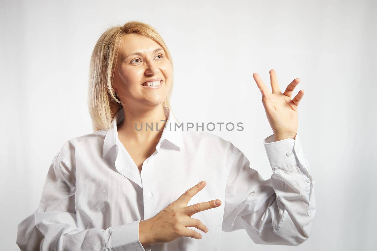 Portrait of a pretty blonde smiling woman posing on white background. Happy girl model in white shirt in studio. Lady winner is joyfull. Copy space