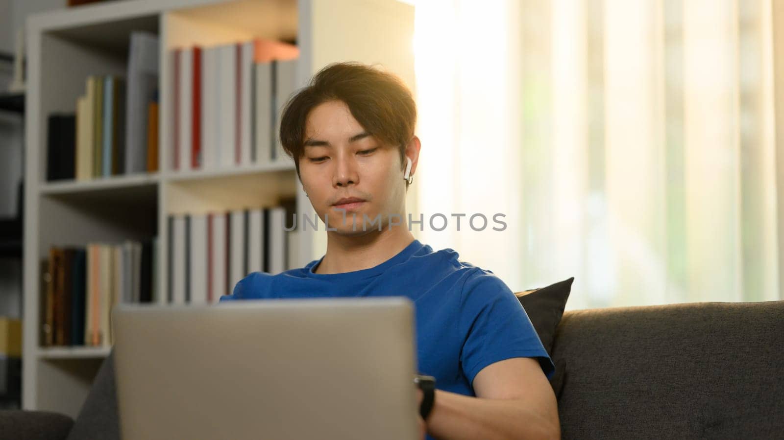 Handsome young asian man working online or browsing internet on laptop at home. Freelance, technology and communication.
