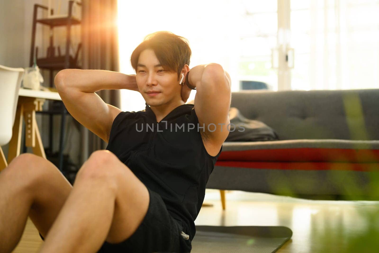Strong asian man wearing sporty clothes doing sit up exercise during home workout. Sport, fitness and healthy lifestyle.