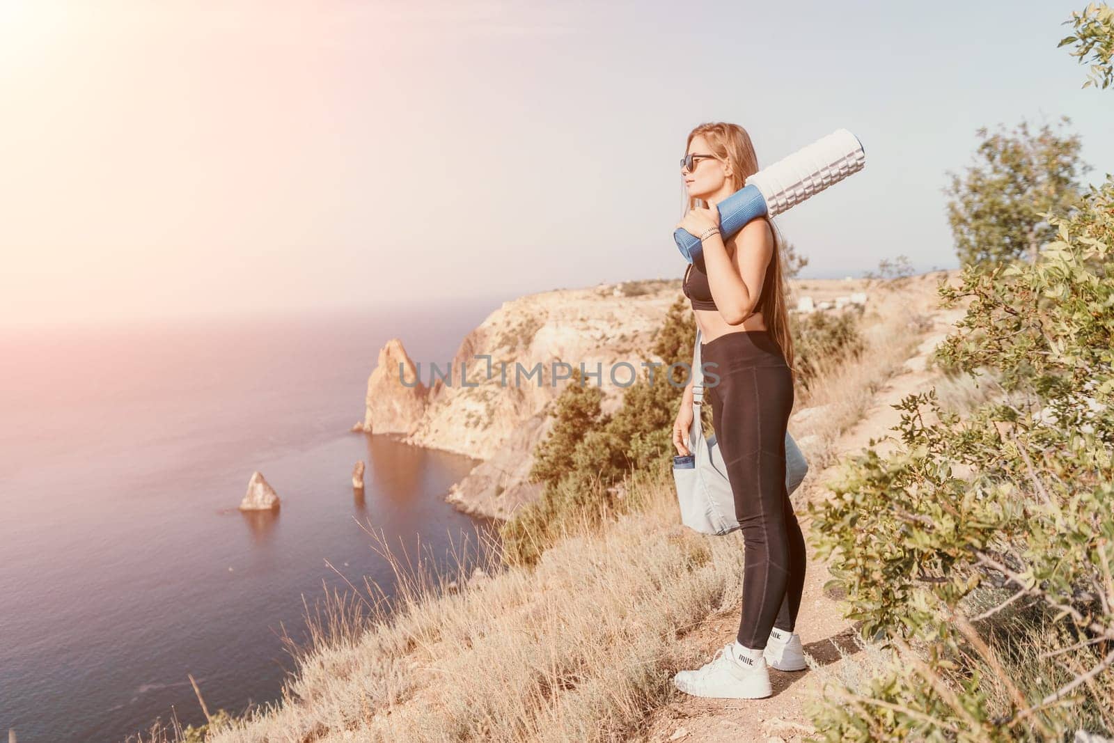 Fitness woman sea. Outdoor workout on yoga mat in park near to ocean beach. Female fitness pilates yoga routine concept. Healthy lifestyle. Happy fit woman exercising with rubber band in park. by panophotograph