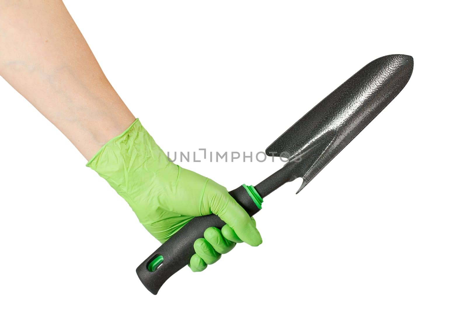 Small garden trowel in woman's hand dressed in a green rubber glove on the gray background.